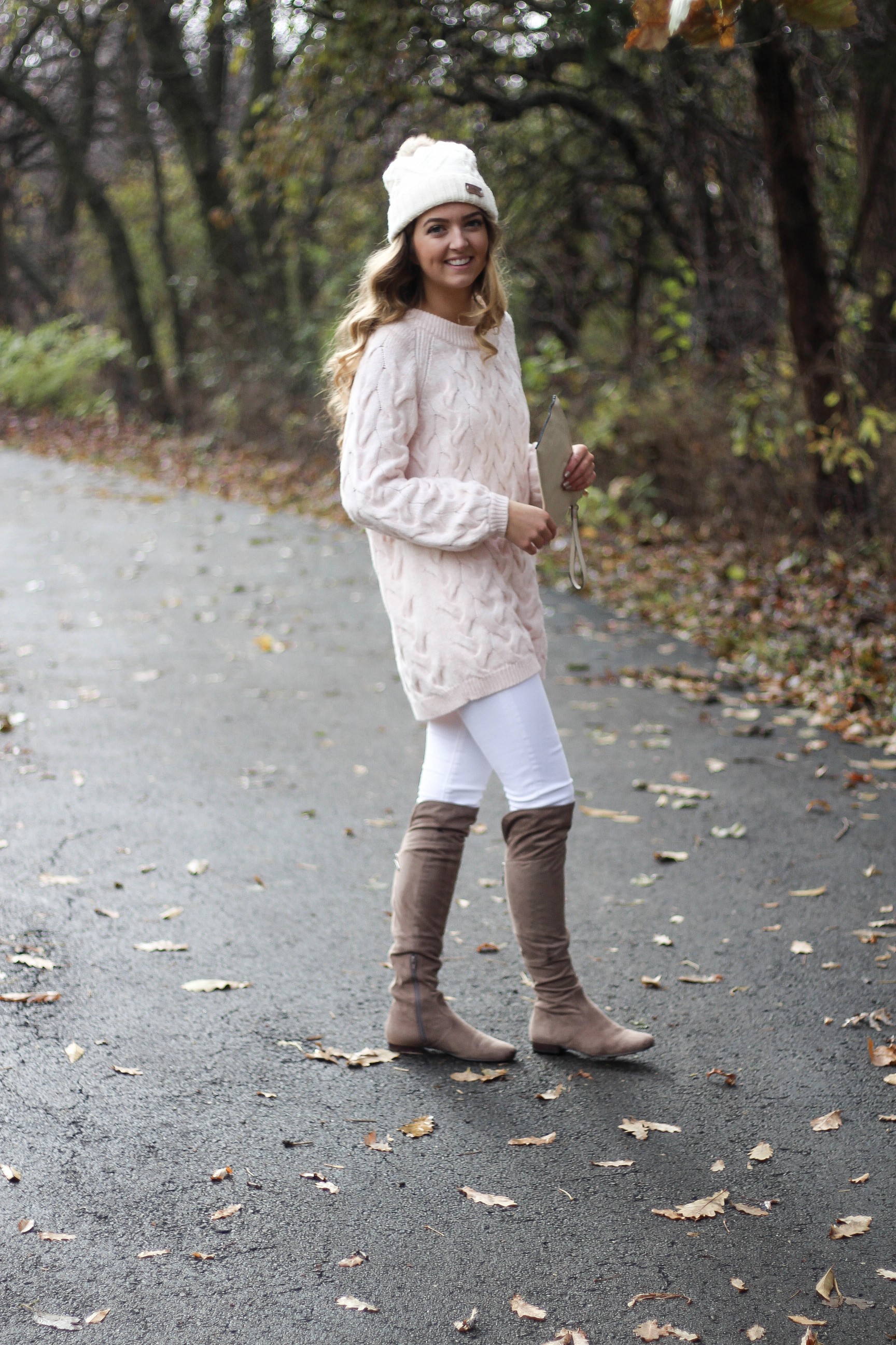 Pink cable knit sweater with white jeans and over the knee tan suede boots topped with an adorable faux fur beanie! The perfect winter outfit by Lauren Lindmark on dailydoseofcharm.com daily dose of charm