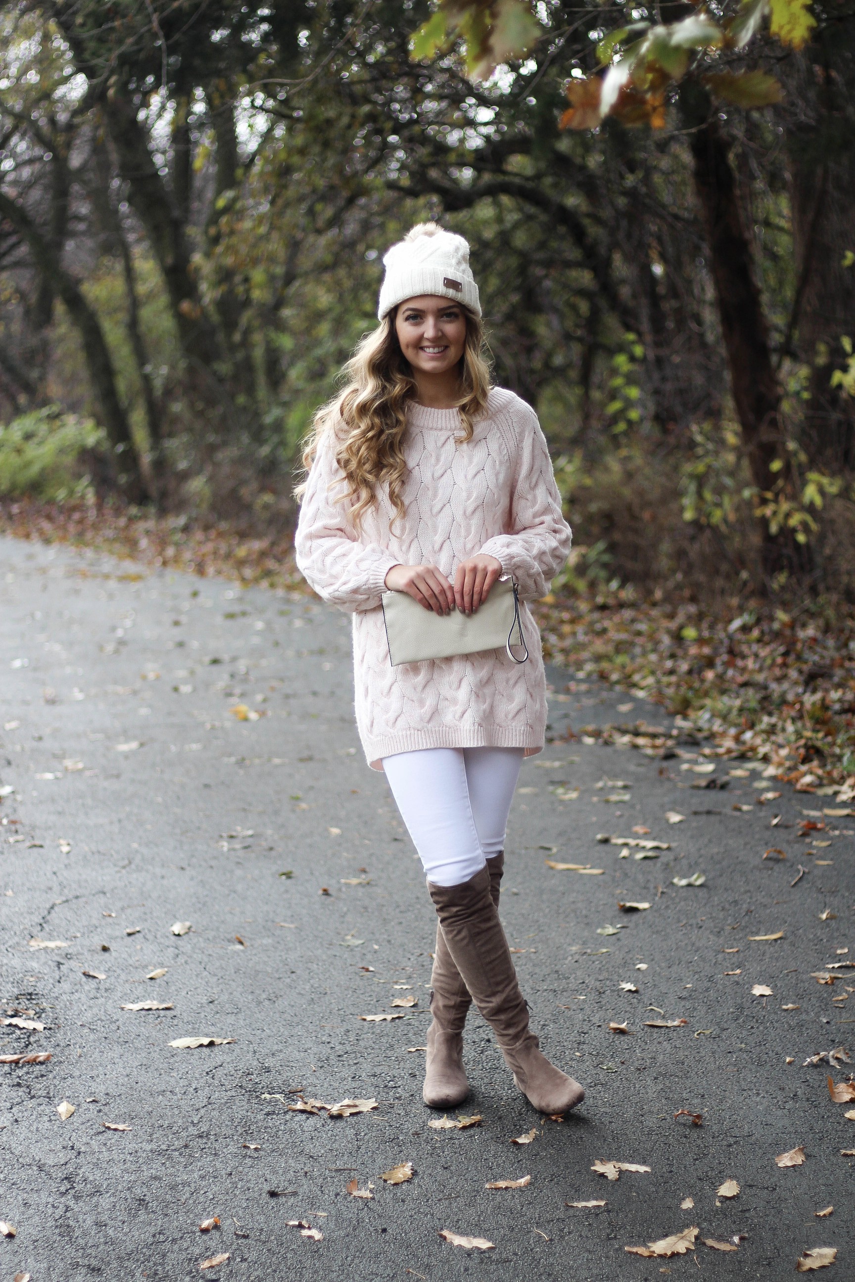 Pink cable knit sweater with white jeans and over the knee tan suede boots topped with an adorable faux fur beanie! The perfect winter outfit by Lauren Lindmark on dailydoseofcharm.com daily dose of charm