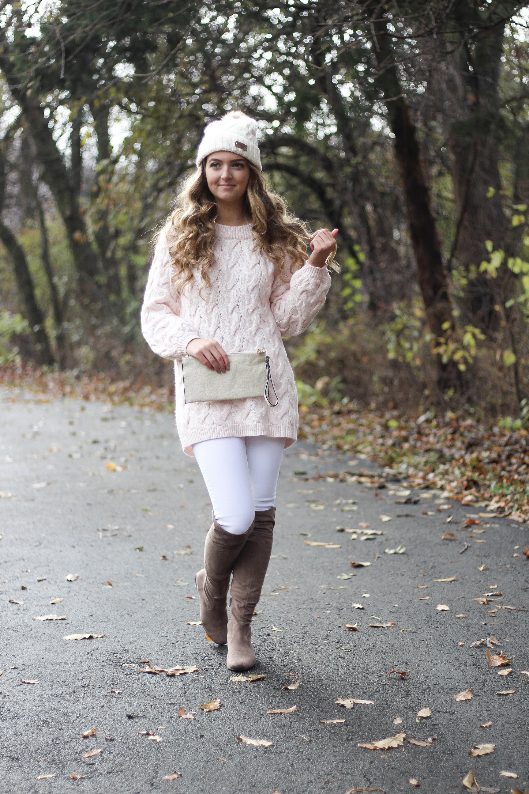 Pink cable knit sweater with white jeans and over the knee tan suede boots topped with an adorable faux fur beanie! The perfect winter outfit by Lauren Lindmark on dailydoseofcharm.com daily dose of charm