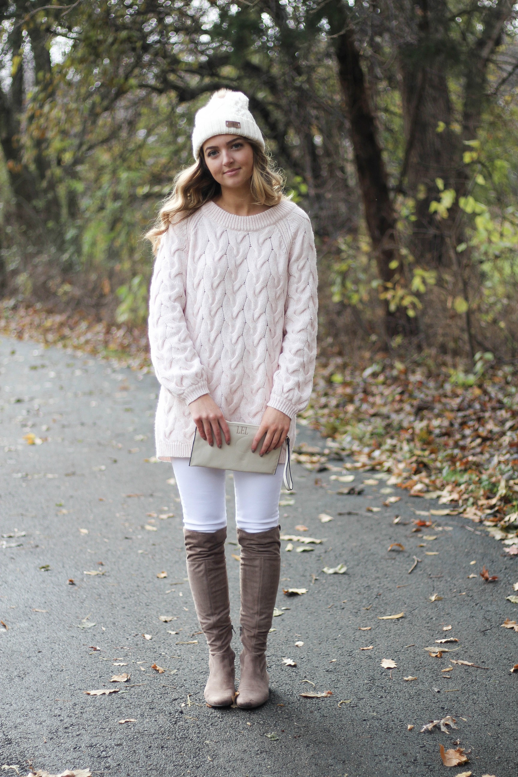 Pink cable knit sweater with white jeans and over the knee tan suede boots topped with an adorable faux fur beanie! The perfect winter outfit by Lauren Lindmark on dailydoseofcharm.com daily dose of charm