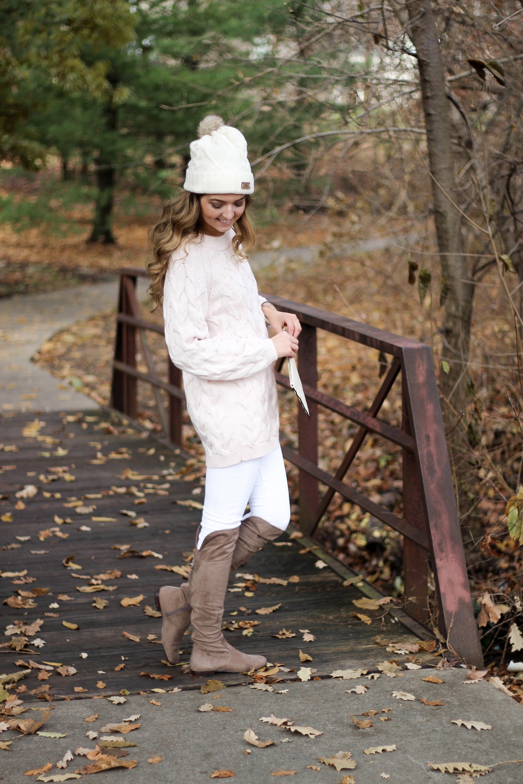 Pink cable knit sweater with white jeans and over the knee tan suede boots topped with an adorable faux fur beanie! The perfect winter outfit by Lauren Lindmark on dailydoseofcharm.com daily dose of charm