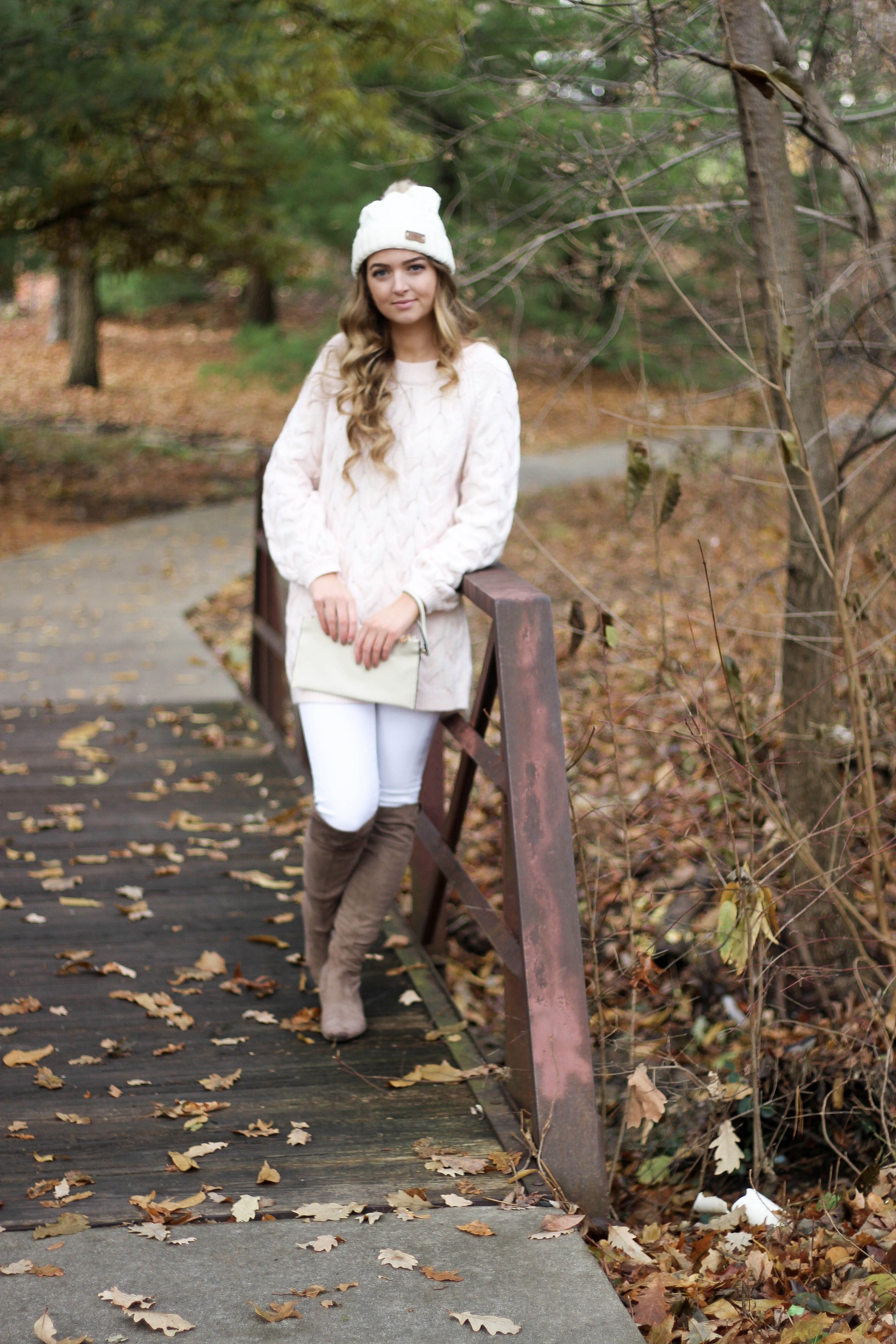 Pink cable knit sweater with white jeans and over the knee tan suede boots topped with an adorable faux fur beanie! The perfect winter outfit by Lauren Lindmark on dailydoseofcharm.com daily dose of charm