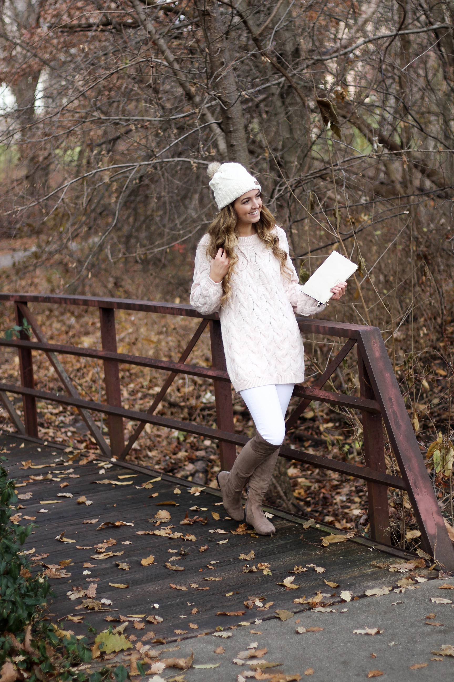 Pink cable knit sweater with white jeans and over the knee tan suede boots topped with an adorable faux fur beanie! The perfect winter outfit by Lauren Lindmark on dailydoseofcharm.com daily dose of charm