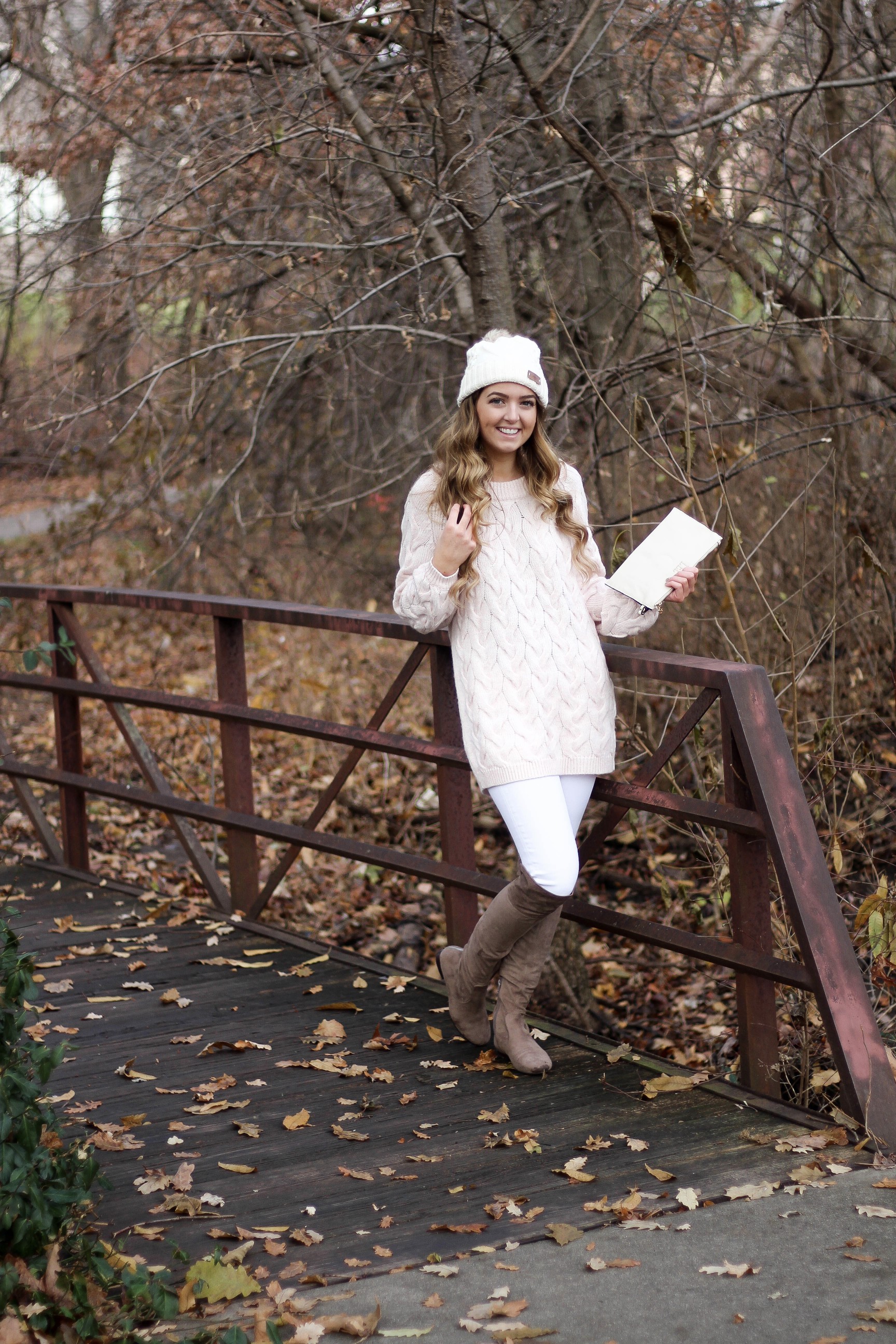 Pink cable knit sweater with white jeans and over the knee tan suede boots topped with an adorable faux fur beanie! The perfect winter outfit by Lauren Lindmark on dailydoseofcharm.com daily dose of charm