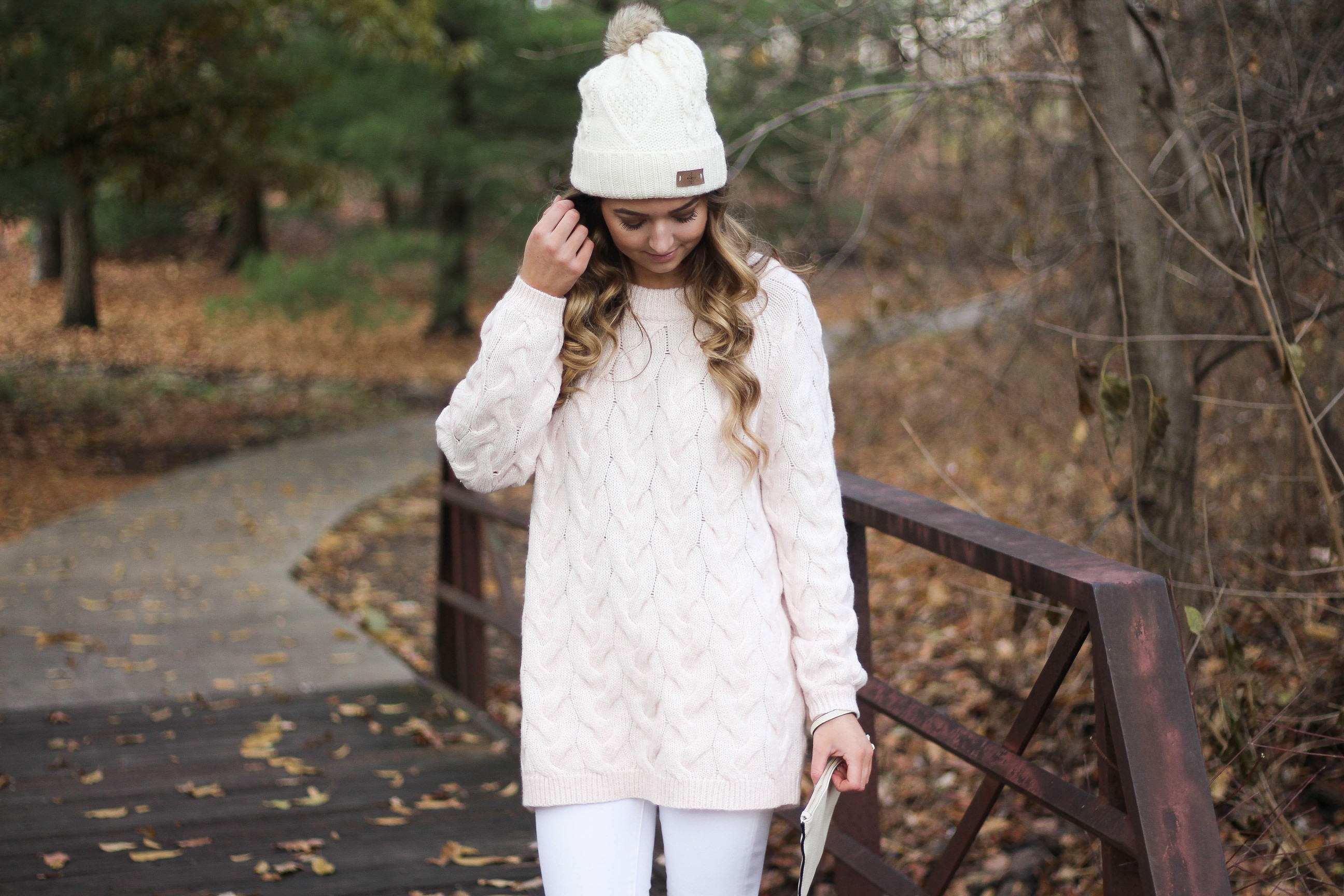 Pink cable knit sweater with white jeans and over the knee tan suede boots topped with an adorable faux fur beanie! The perfect winter outfit by Lauren Lindmark on dailydoseofcharm.com daily dose of charm