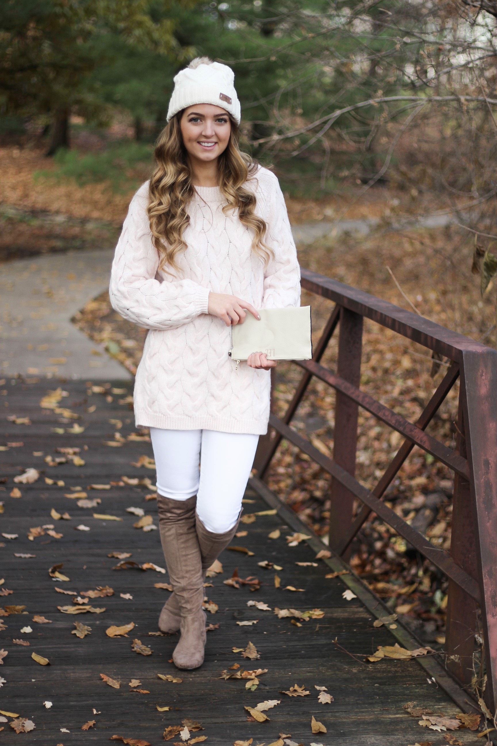 Pink cable knit sweater with white jeans and over the knee tan suede boots topped with an adorable faux fur beanie! The perfect winter outfit by Lauren Lindmark on dailydoseofcharm.com daily dose of charm