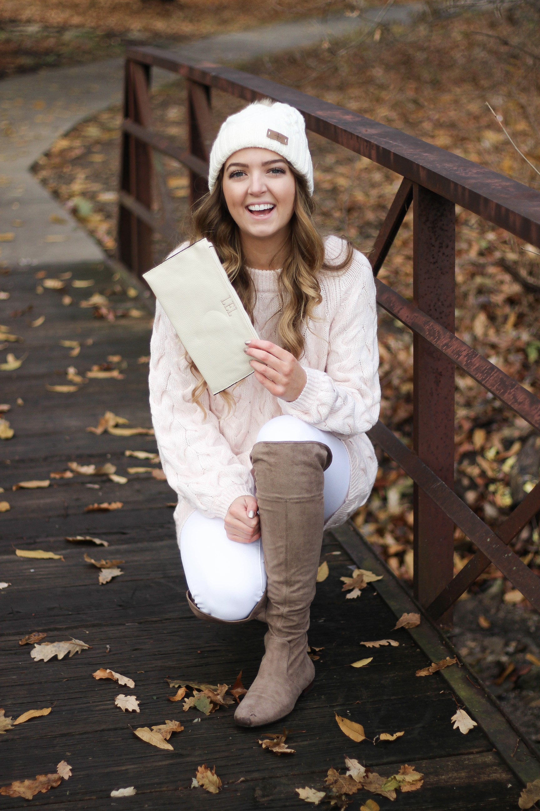 Pink cable knit sweater with white jeans and over the knee tan suede boots topped with an adorable faux fur beanie! The perfect winter outfit by Lauren Lindmark on dailydoseofcharm.com daily dose of charm