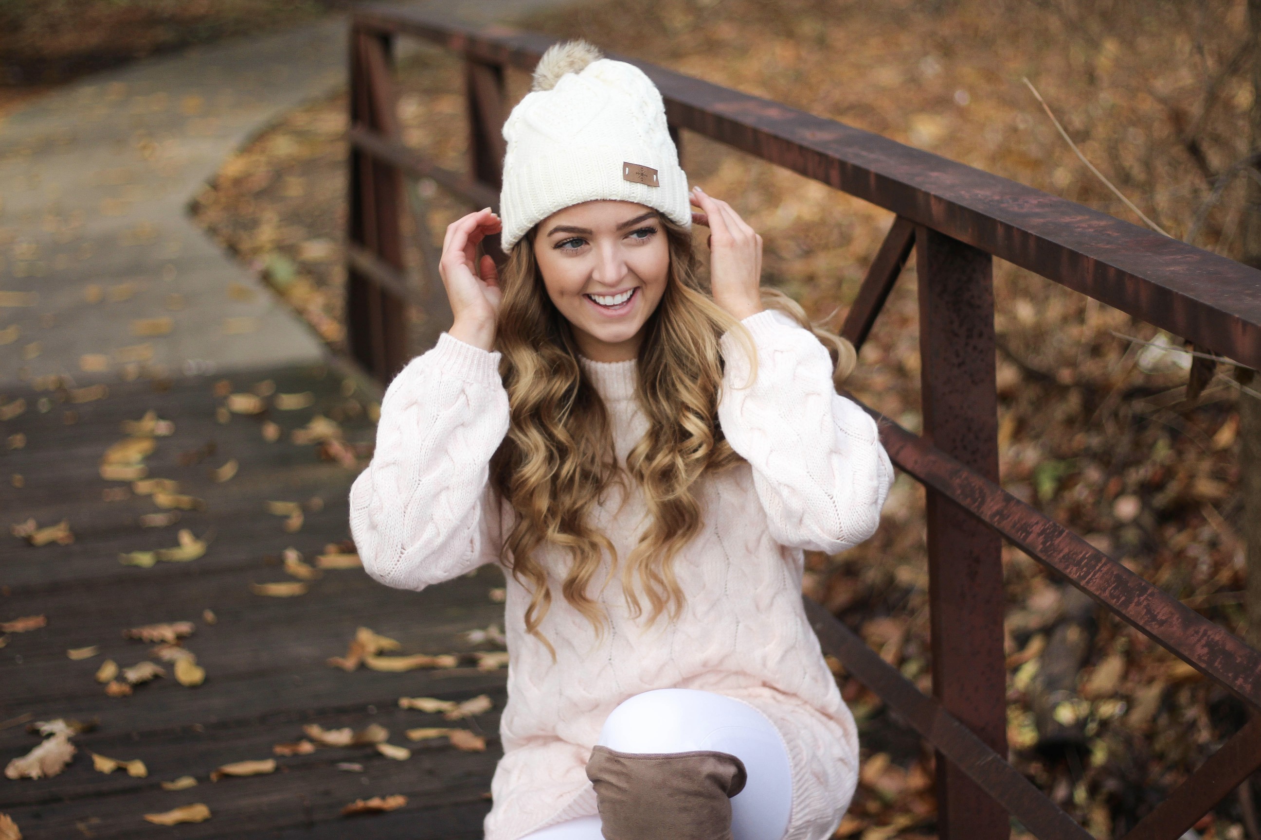 Pink cable knit sweater with white jeans and over the knee tan suede boots topped with an adorable faux fur beanie! The perfect winter outfit by Lauren Lindmark on dailydoseofcharm.com daily dose of charm