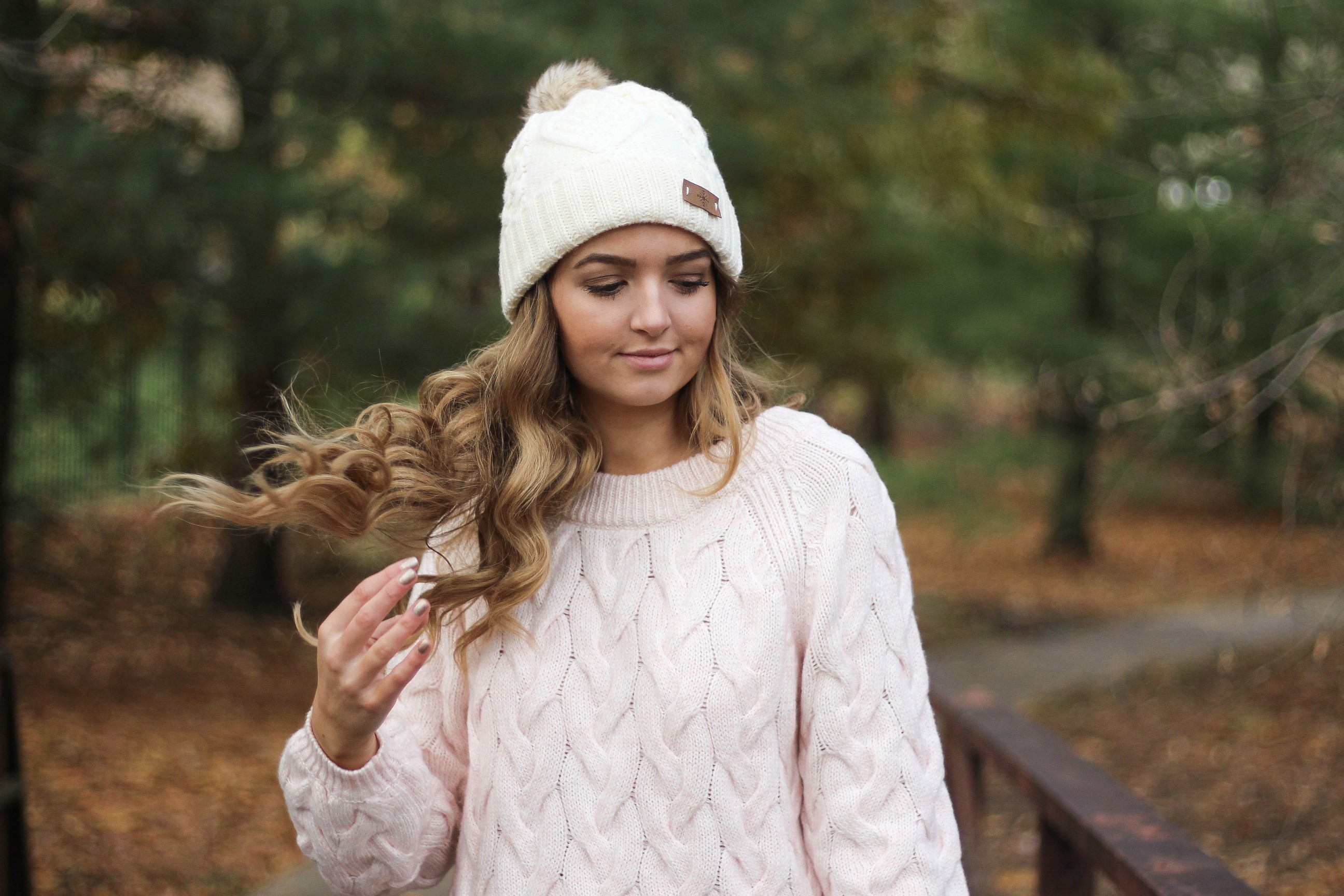 Pink cable knit sweater with white jeans and over the knee tan suede boots topped with an adorable faux fur beanie! The perfect winter outfit by Lauren Lindmark on dailydoseofcharm.com daily dose of charm