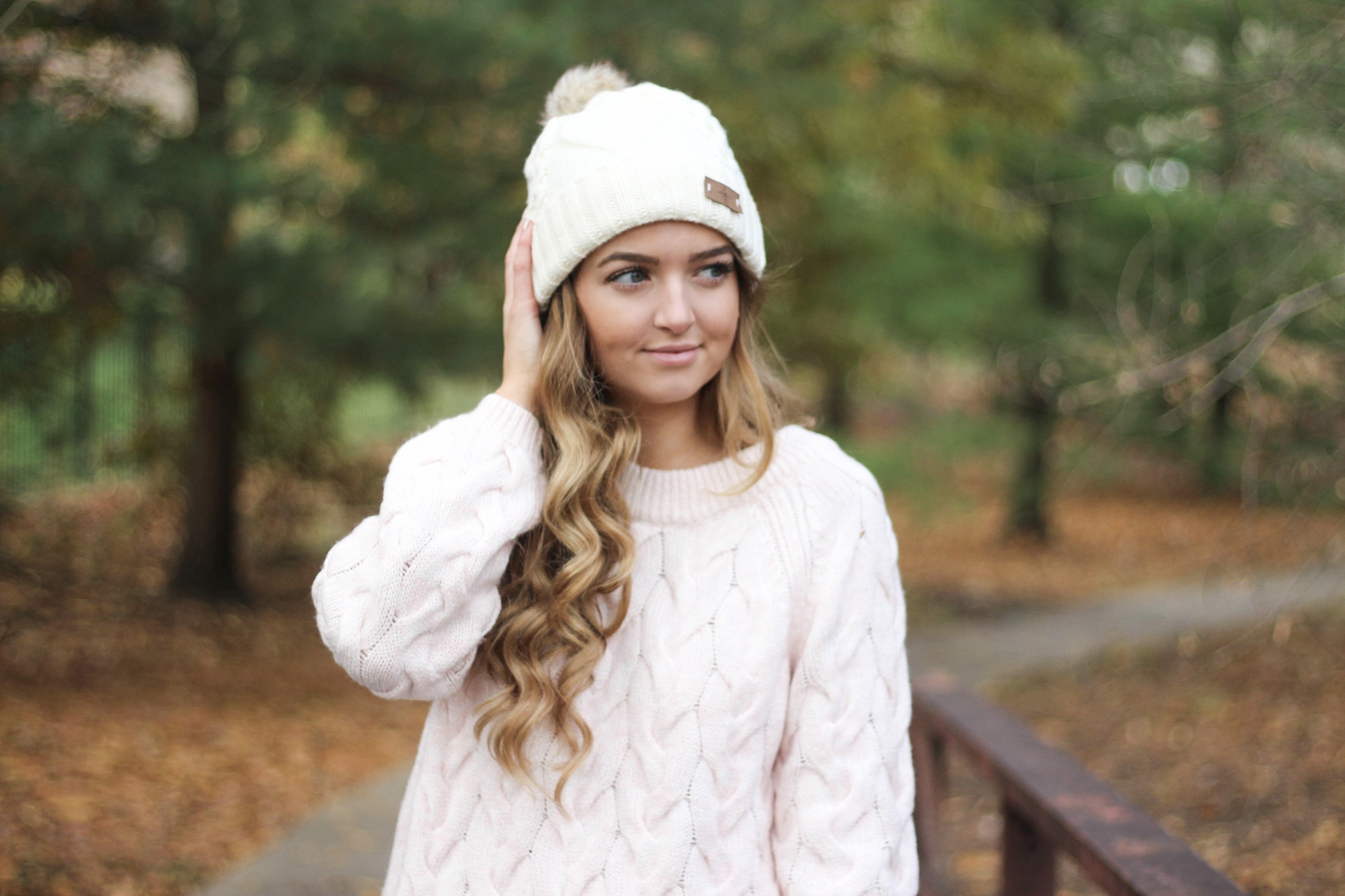 Pink cable knit sweater with white jeans and over the knee tan suede boots topped with an adorable faux fur beanie! The perfect winter outfit by Lauren Lindmark on dailydoseofcharm.com daily dose of charm