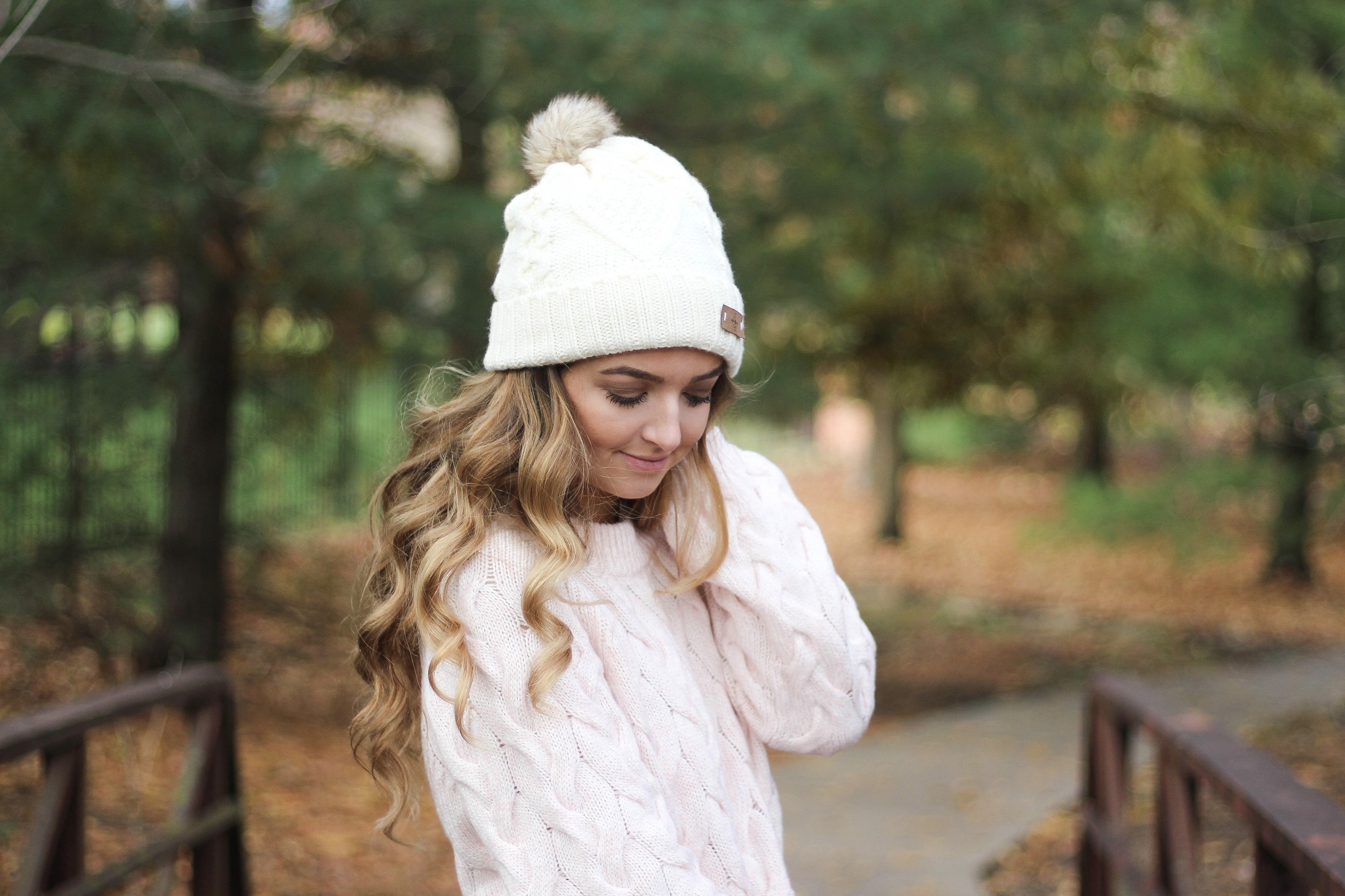 Pink cable knit sweater with white jeans and over the knee tan suede boots topped with an adorable faux fur beanie! The perfect winter outfit by Lauren Lindmark on dailydoseofcharm.com daily dose of charm