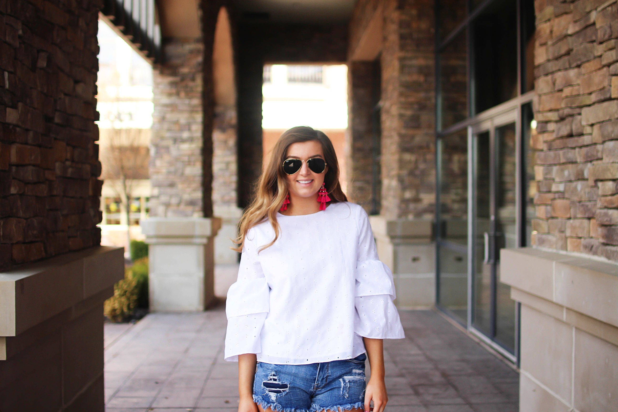 The cutest fiesta top ever! The ruffle sleeves on the top are so unique and such a cute outfit idea! I paired it with ripped jeans shorts and my tassel sandals and Kate Spade tassel earrings! By Lauren Lindmark on dailydoseofcharm.com daily dose of charm