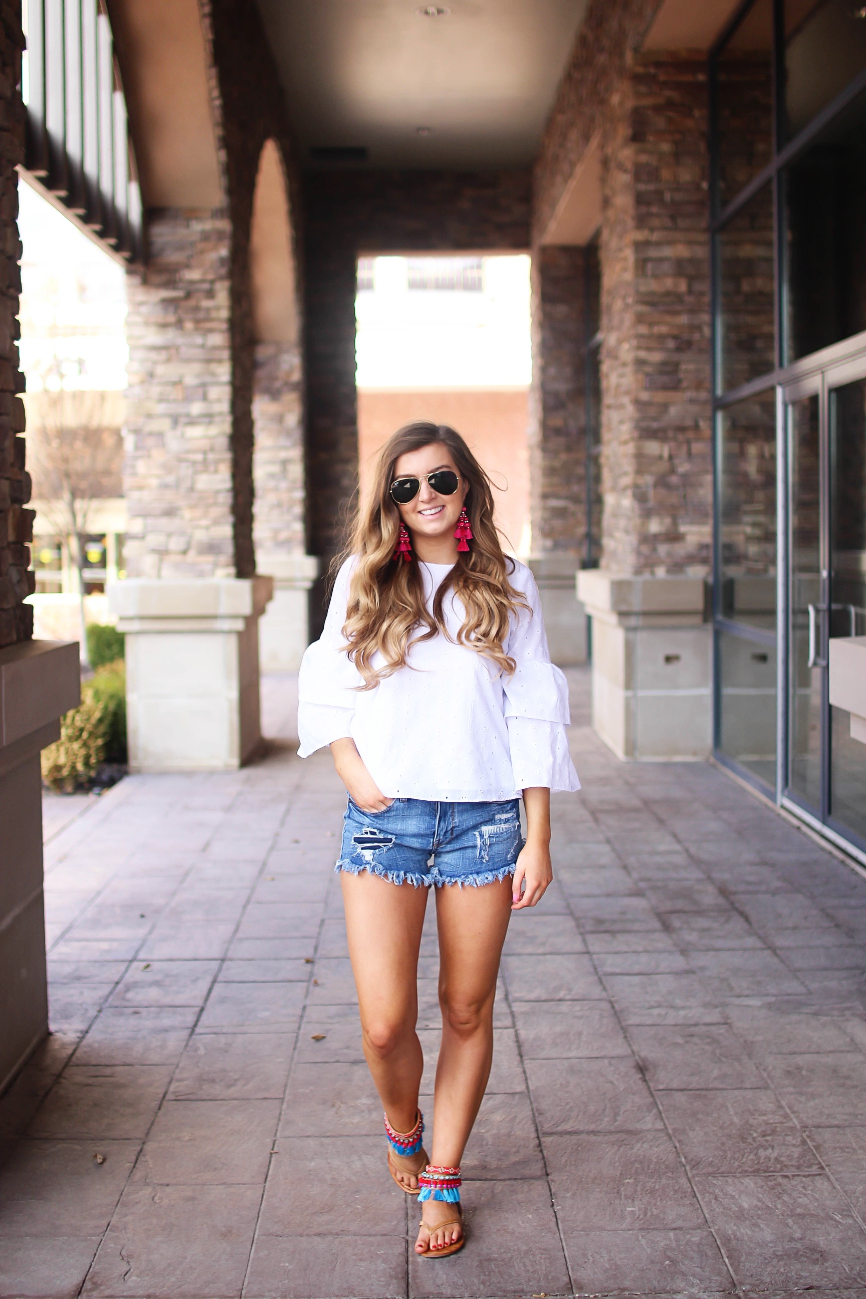 The cutest fiesta top ever! The ruffle sleeves on the top are so unique and such a cute outfit idea! I paired it with ripped jeans shorts and my tassel sandals and Kate Spade tassel earrings! By Lauren Lindmark on dailydoseofcharm.com daily dose of charm
