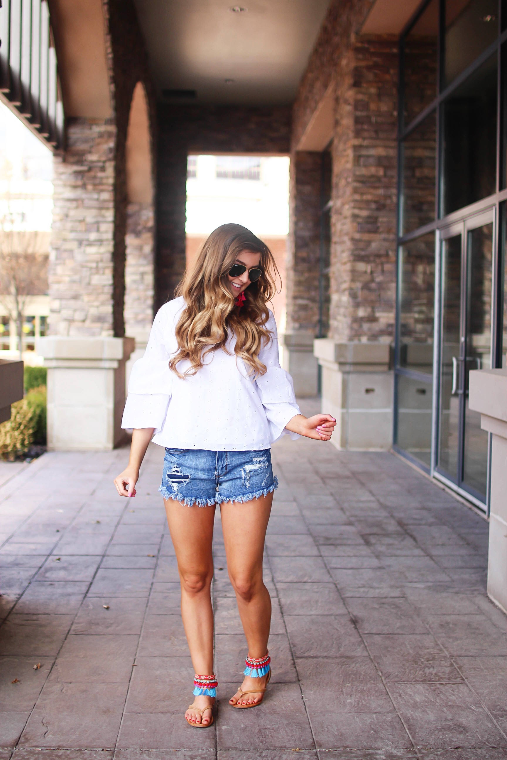 The cutest fiesta top ever! The ruffle sleeves on the top are so unique and such a cute outfit idea! I paired it with ripped jeans shorts and my tassel sandals and Kate Spade tassel earrings! By Lauren Lindmark on dailydoseofcharm.com daily dose of charm