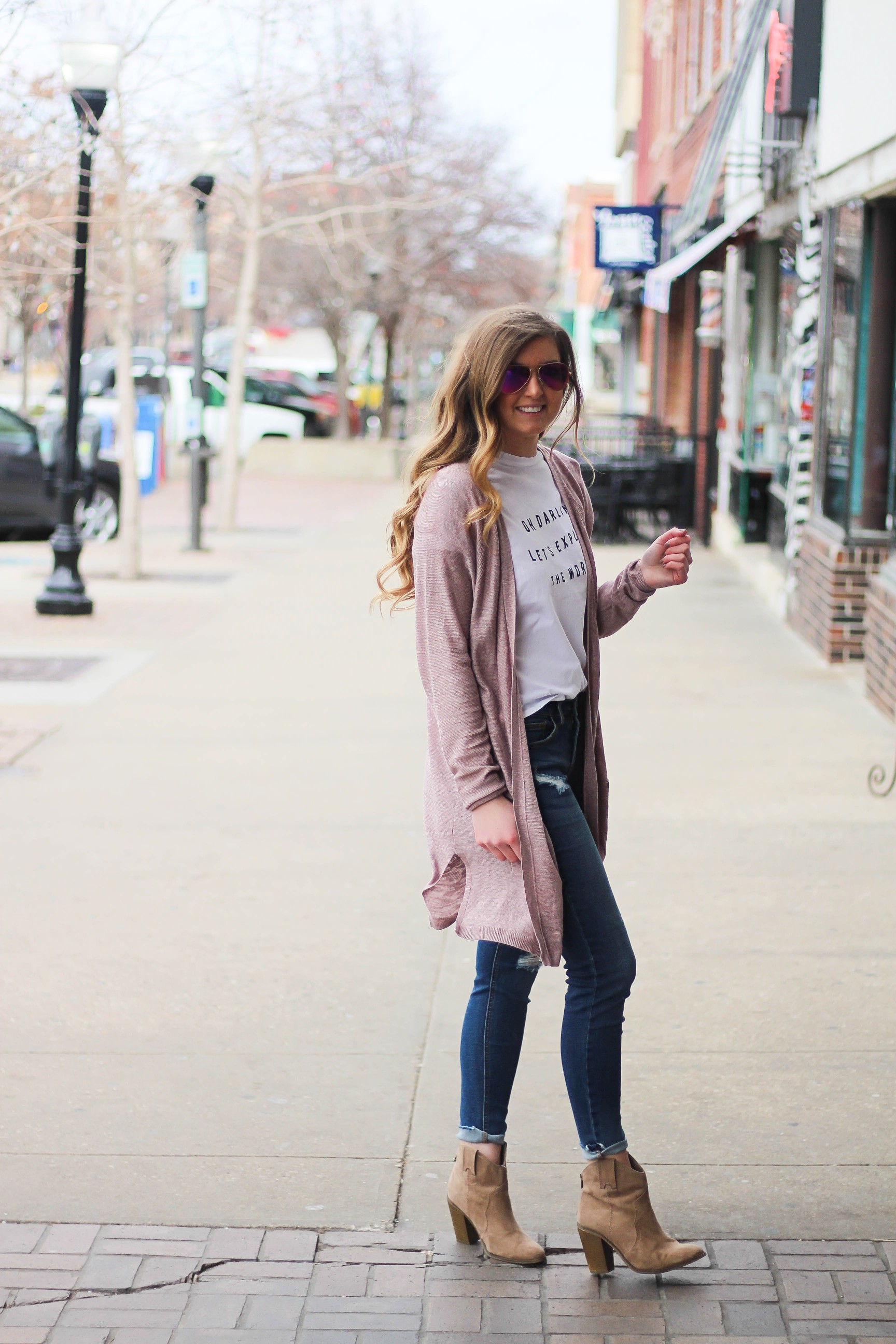 The cutest purple/pink cardigan for spring paired with my Oh Darling Let's Explore the World tee! I love this tee because it matches my wanderlust! I paired it with my favorite ripped jeans and tan suede booties. Plus of course my pink ray bans! By Lauren Lindmark on Daily Dose of Charm