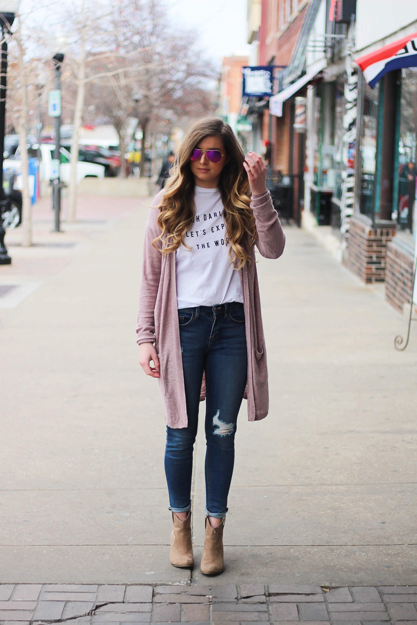 The cutest purple/pink cardigan for spring paired with my Oh Darling Let's Explore the World tee! I love this tee because it matches my wanderlust! I paired it with my favorite ripped jeans and tan suede booties. Plus of course my pink ray bans! By Lauren Lindmark on Daily Dose of Charm