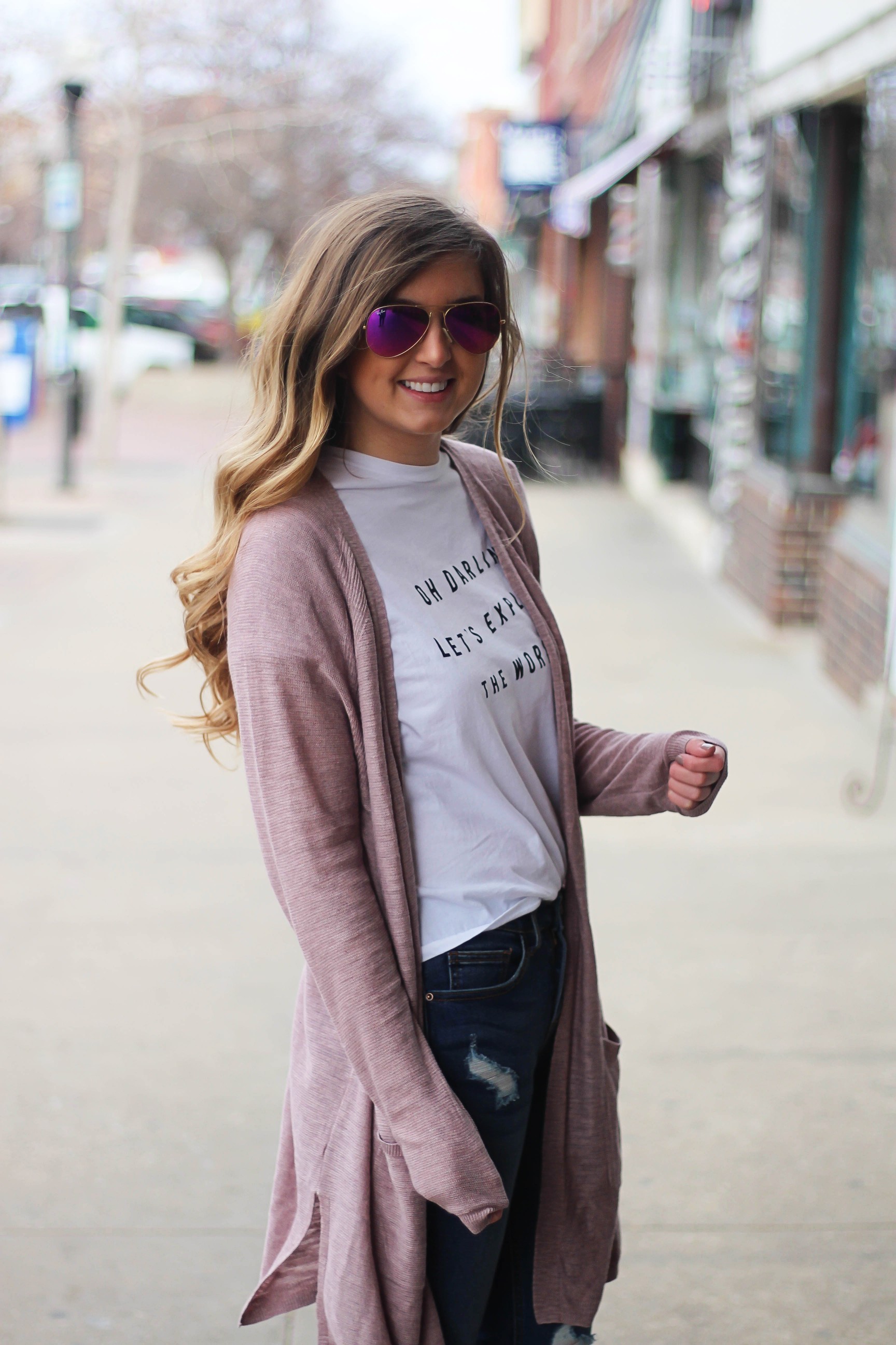 The cutest purple/pink cardigan for spring paired with my Oh Darling Let's Explore the World tee! I love this tee because it matches my wanderlust! I paired it with my favorite ripped jeans and tan suede booties. Plus of course my pink ray bans! By Lauren Lindmark on Daily Dose of Charm