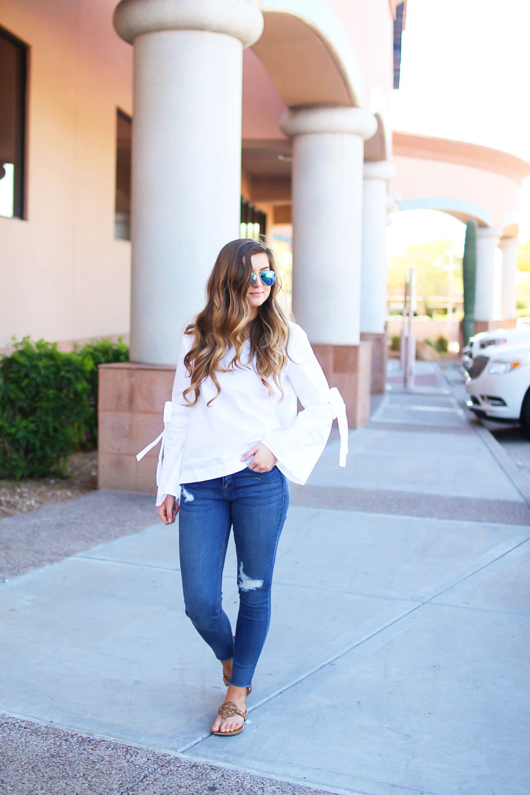 Love this white bow sleeve top that's only $28! It's so cute and classy, plus can be worn with so many things! I paired this top with my favorite ripped jeans, tory burch miller, and blue mirrored ray ban aviators! By Lauren Lindmark on dailydoseofcharm.com daily dose of charm