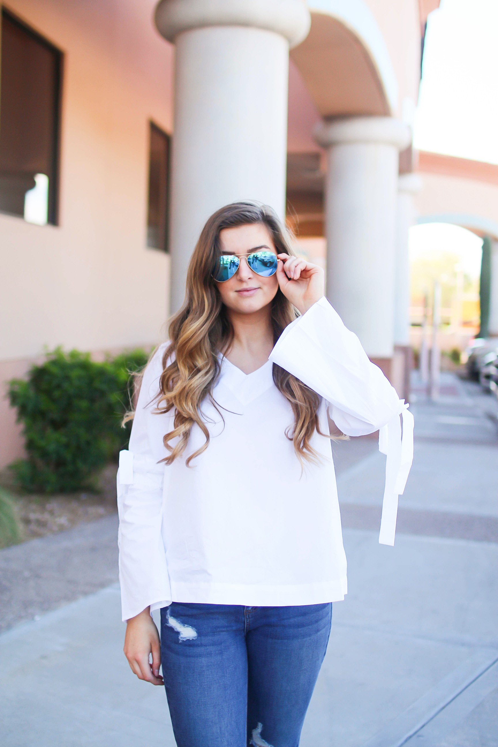 Love this white bow sleeve top that's only $28! It's so cute and classy, plus can be worn with so many things! I paired this top with my favorite ripped jeans, tory burch miller, and blue mirrored ray ban aviators! By Lauren Lindmark on dailydoseofcharm.com daily dose of charm