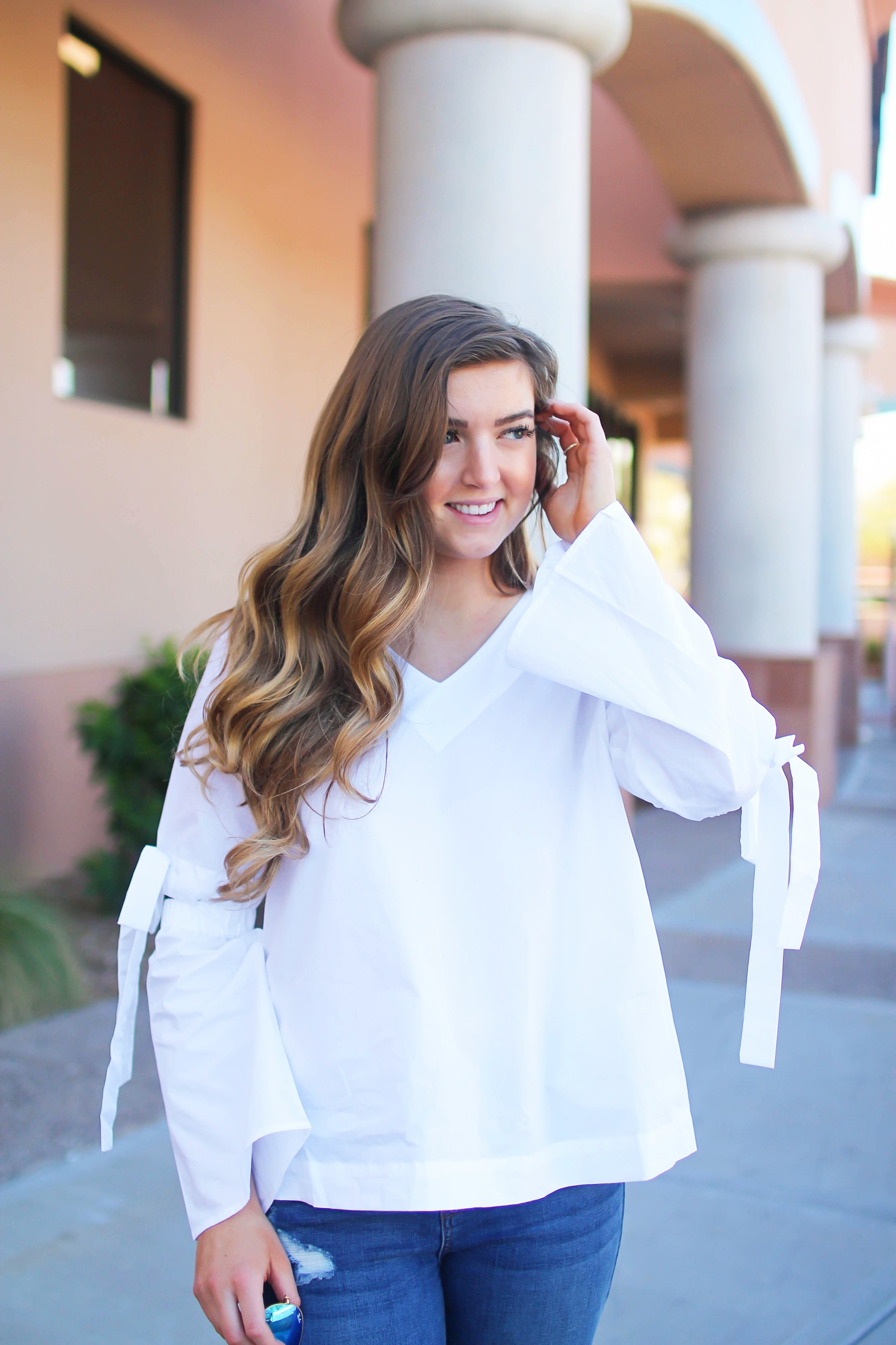 Love this white bow sleeve top that's only $28! It's so cute and classy, plus can be worn with so many things! I paired this top with my favorite ripped jeans, tory burch miller, and blue mirrored ray ban aviators! By Lauren Lindmark on dailydoseofcharm.com daily dose of charm