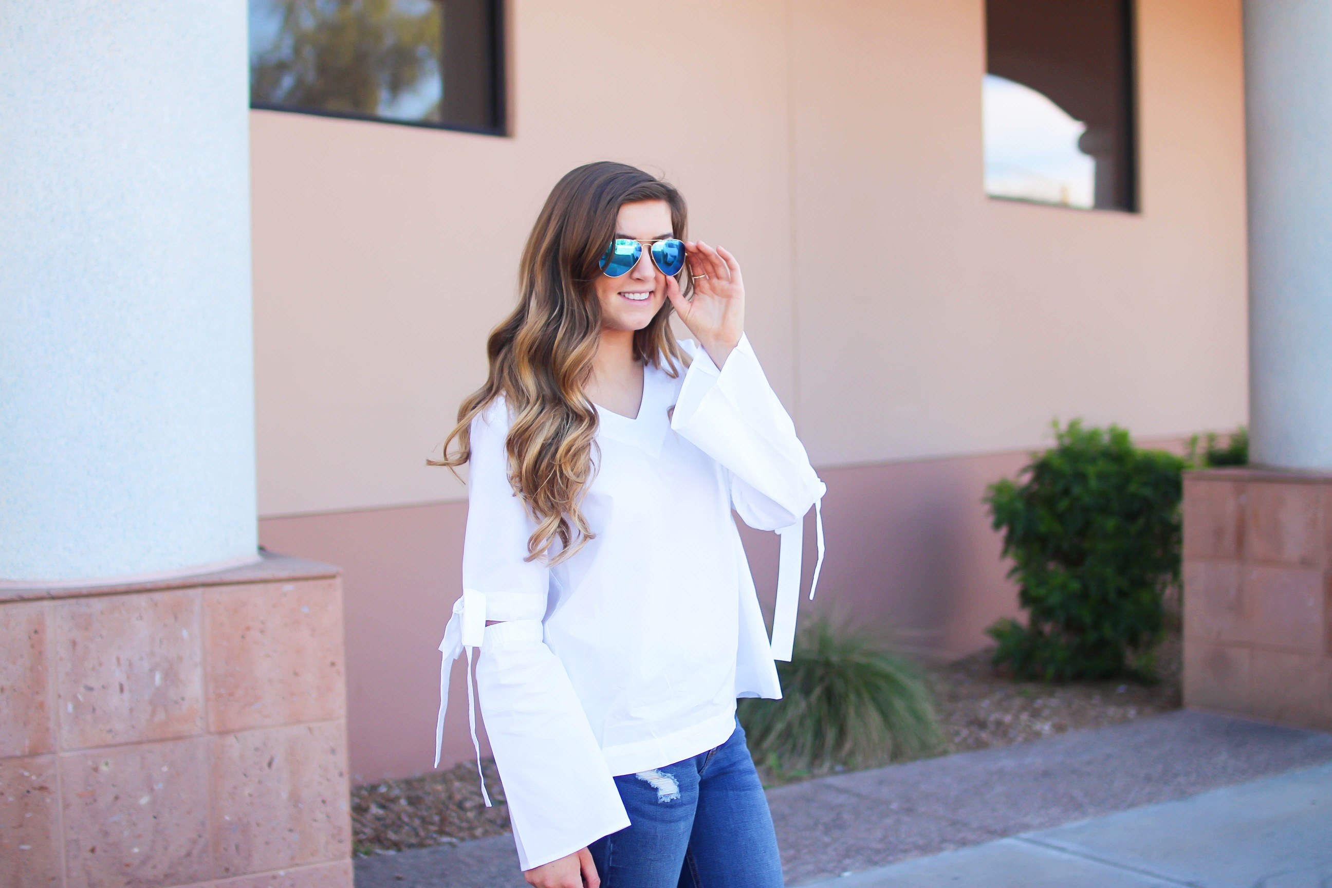 Love this white bow sleeve top that's only $28! It's so cute and classy, plus can be worn with so many things! I paired this top with my favorite ripped jeans, tory burch miller, and blue mirrored ray ban aviators! By Lauren Lindmark on dailydoseofcharm.com daily dose of charm