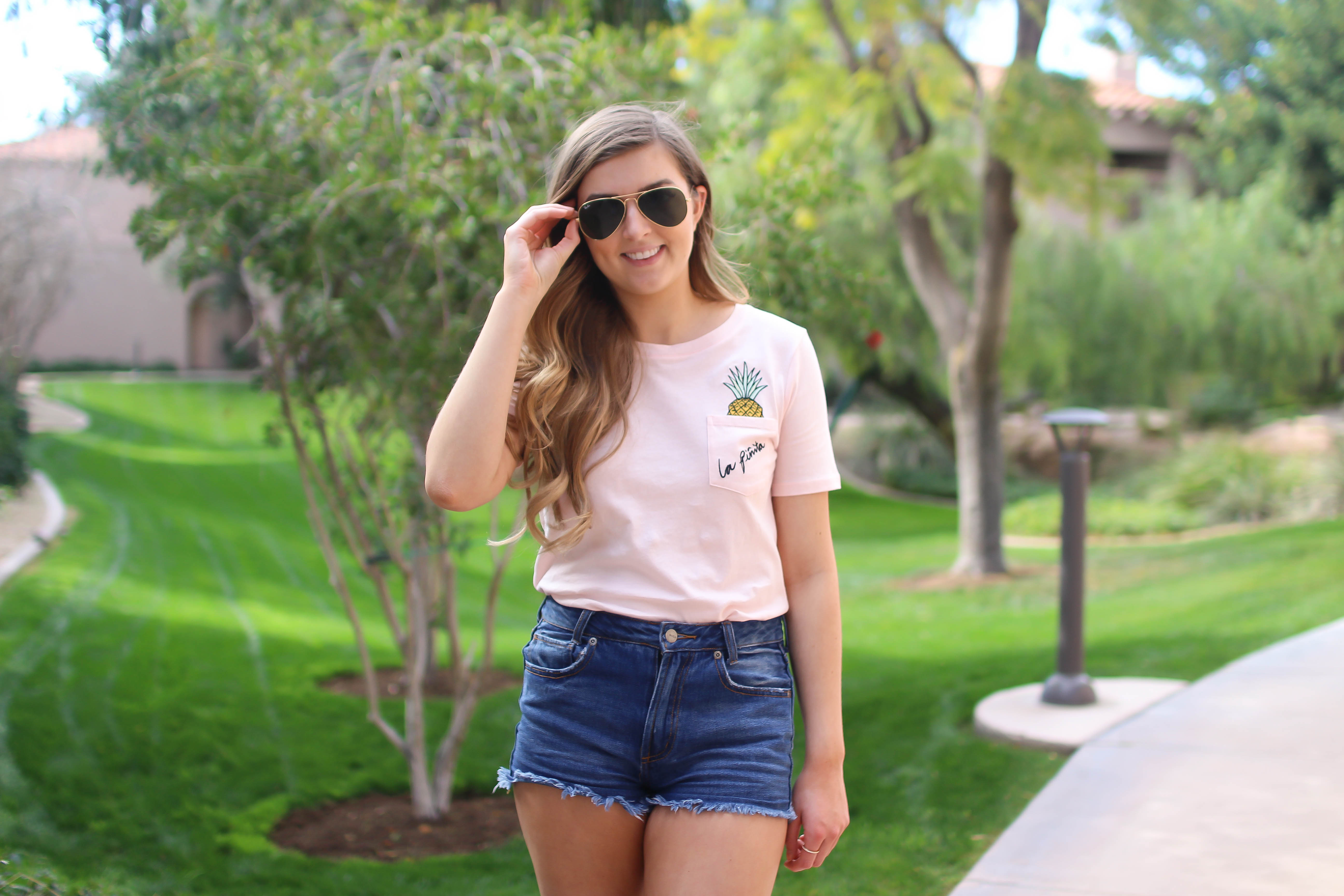 The cutest pink pineapple tee perfect for spring break and summer look! Perfect outfit idea for spring and summer! Paired with jean shorts and Gold New Balance shoes. By Lauren Lindmark on Daily Dose of Charm dailydoseofcharm.com