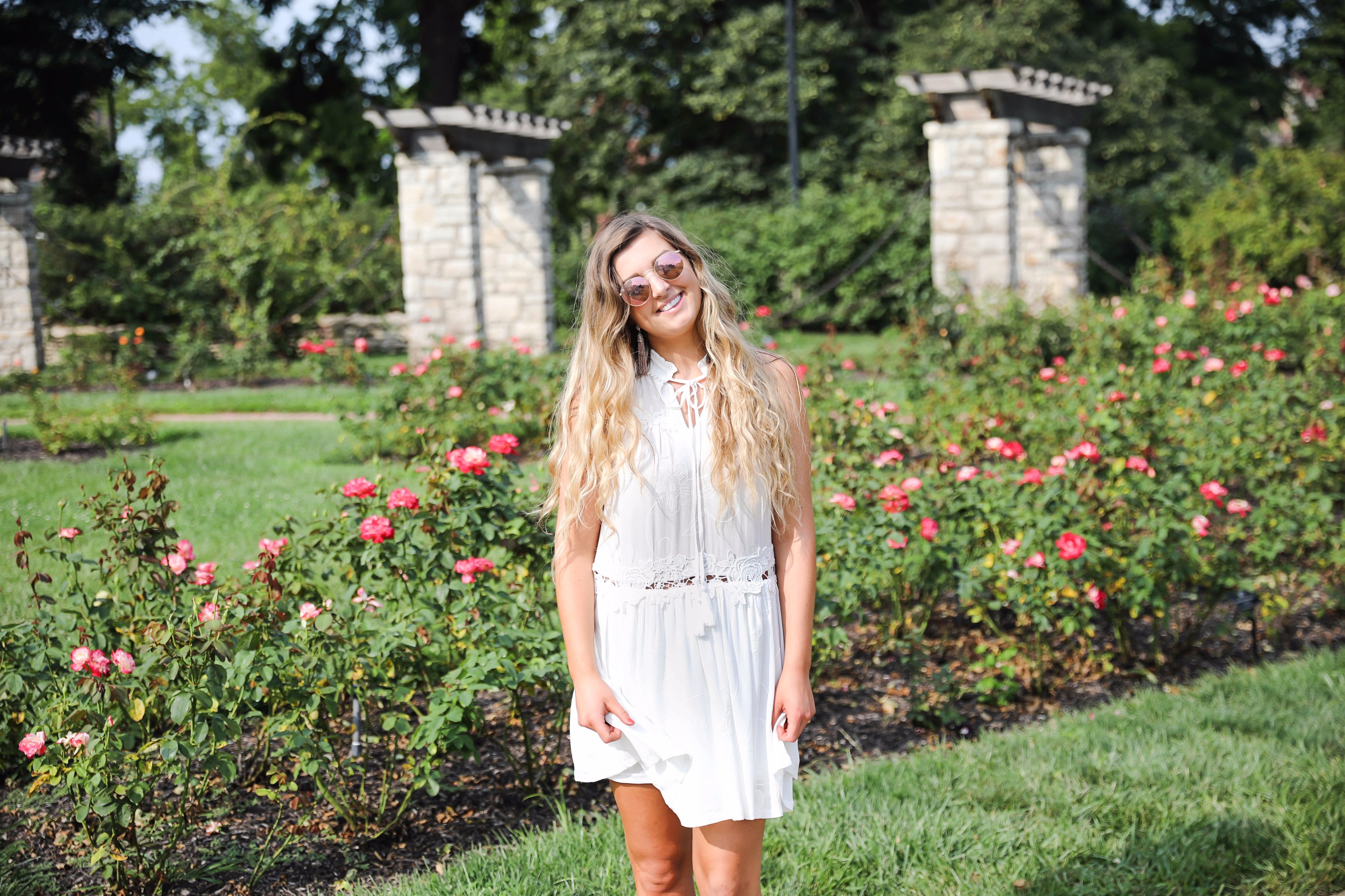 Flowy white dress surrounded by flowers! I love this dress, it's so fun and flowy and it looks so good with booties to transition into fall! Find details on fashion blogger daily dose of charm by lauren lindmark
