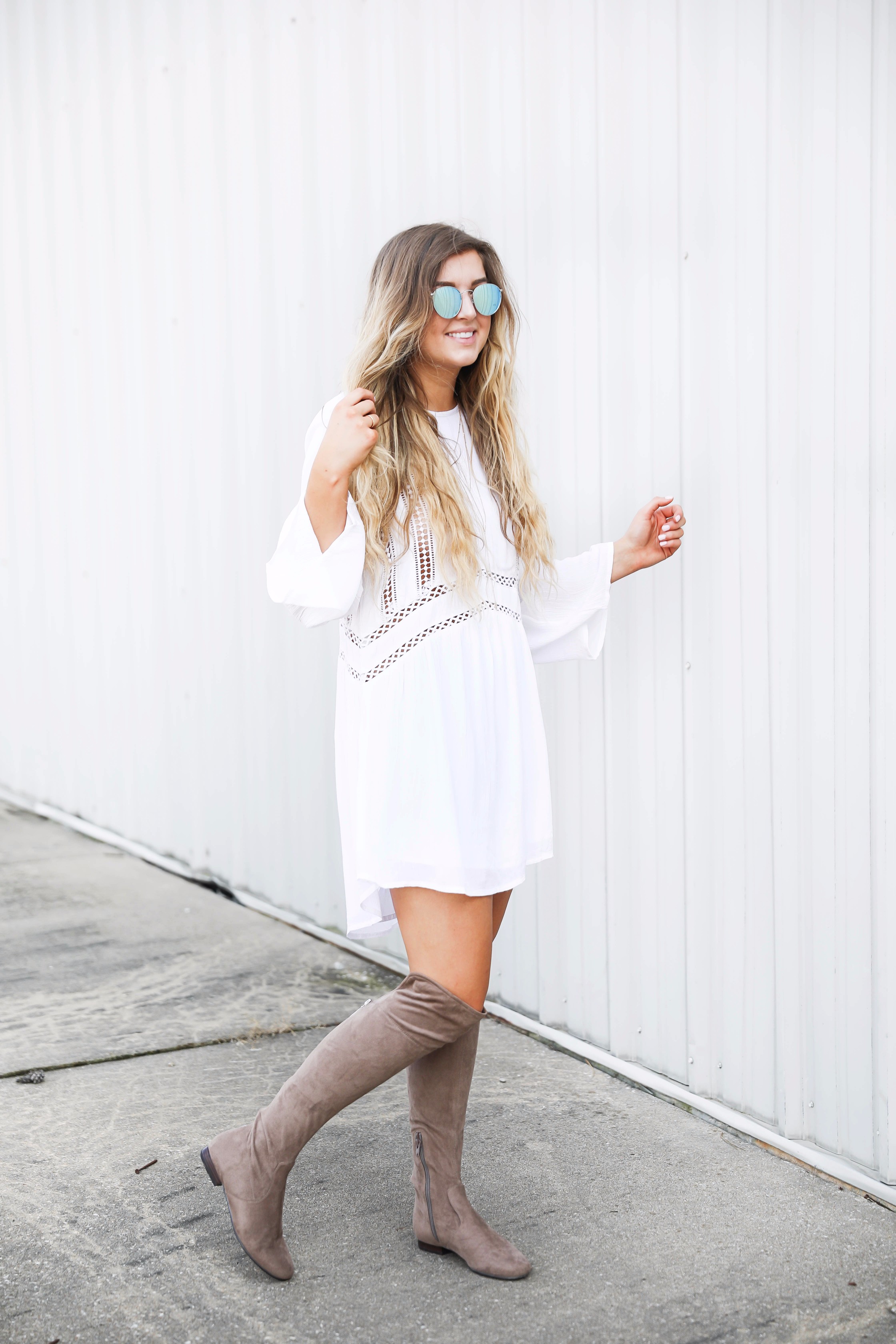 White boho cutout dress with over the knee light brown suede boots! Paired with light blue circle sunglasses. Such a cute dress for summer going into fall! Find the details on fashion blog daily dose of charm by lauren lindmark