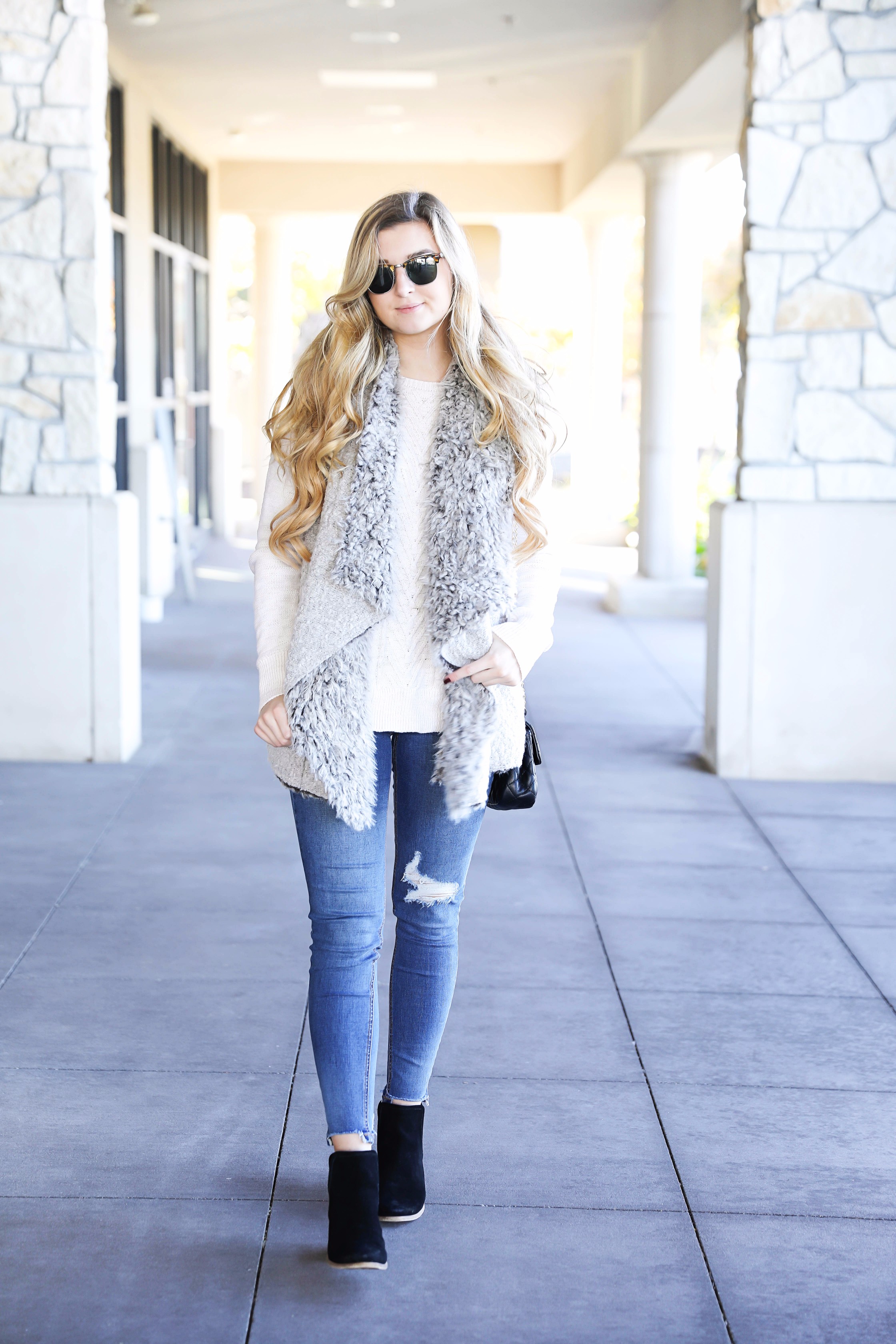 Fuzzy vest with cable knit sweater! Paired with my favorite ripped jeans and clubmaster sunglasses. These black booties are the best! Details on fashion blog daily dose of charm by lauren lindmark