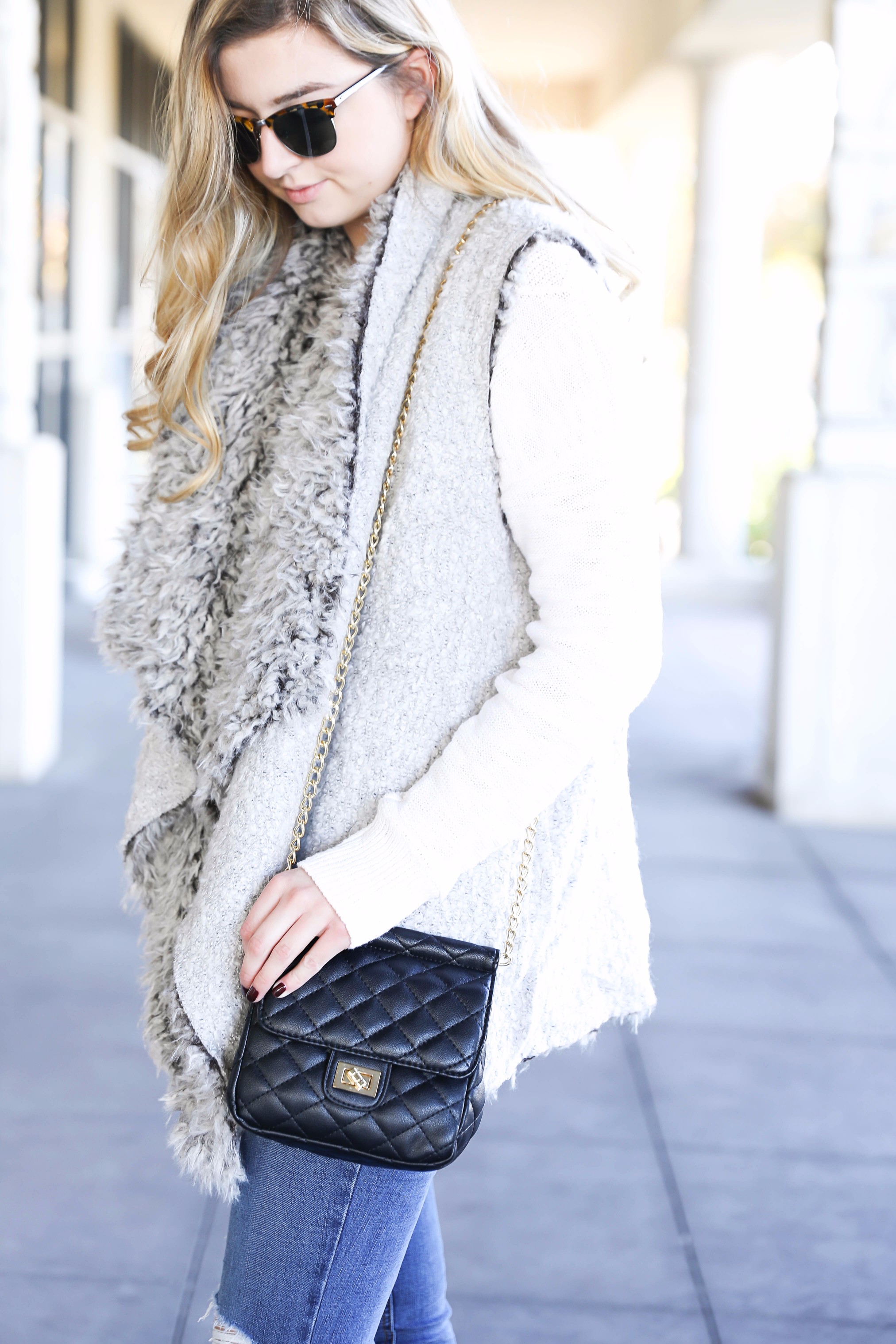 Fuzzy vest with cable knit sweater! Paired with my favorite ripped jeans and clubmaster sunglasses. These black booties are the best! Details on fashion blog daily dose of charm by lauren lindmark