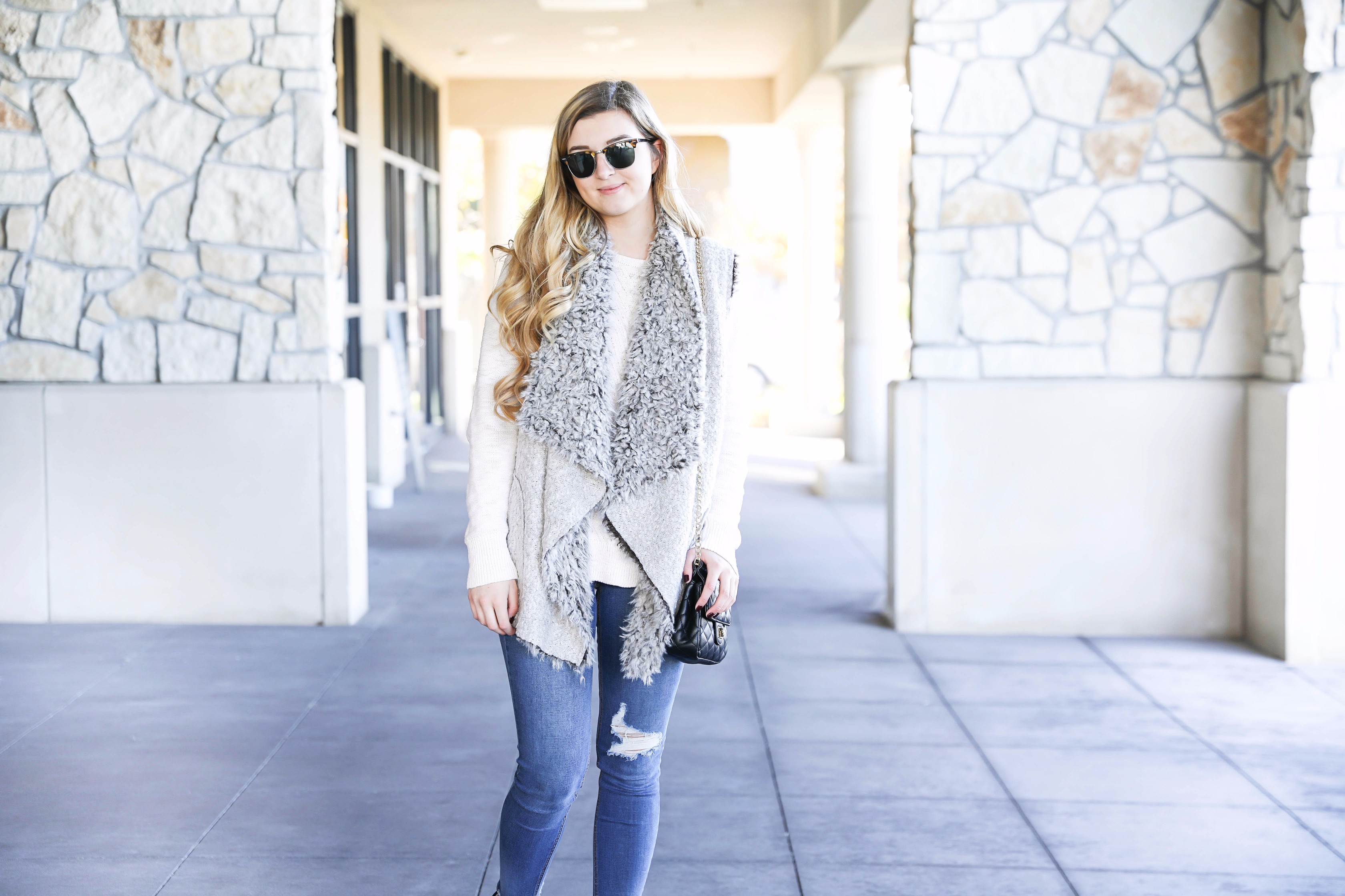 Fuzzy vest with cable knit sweater! Paired with my favorite ripped jeans and clubmaster sunglasses. These black booties are the best! Details on fashion blog daily dose of charm by lauren lindmark