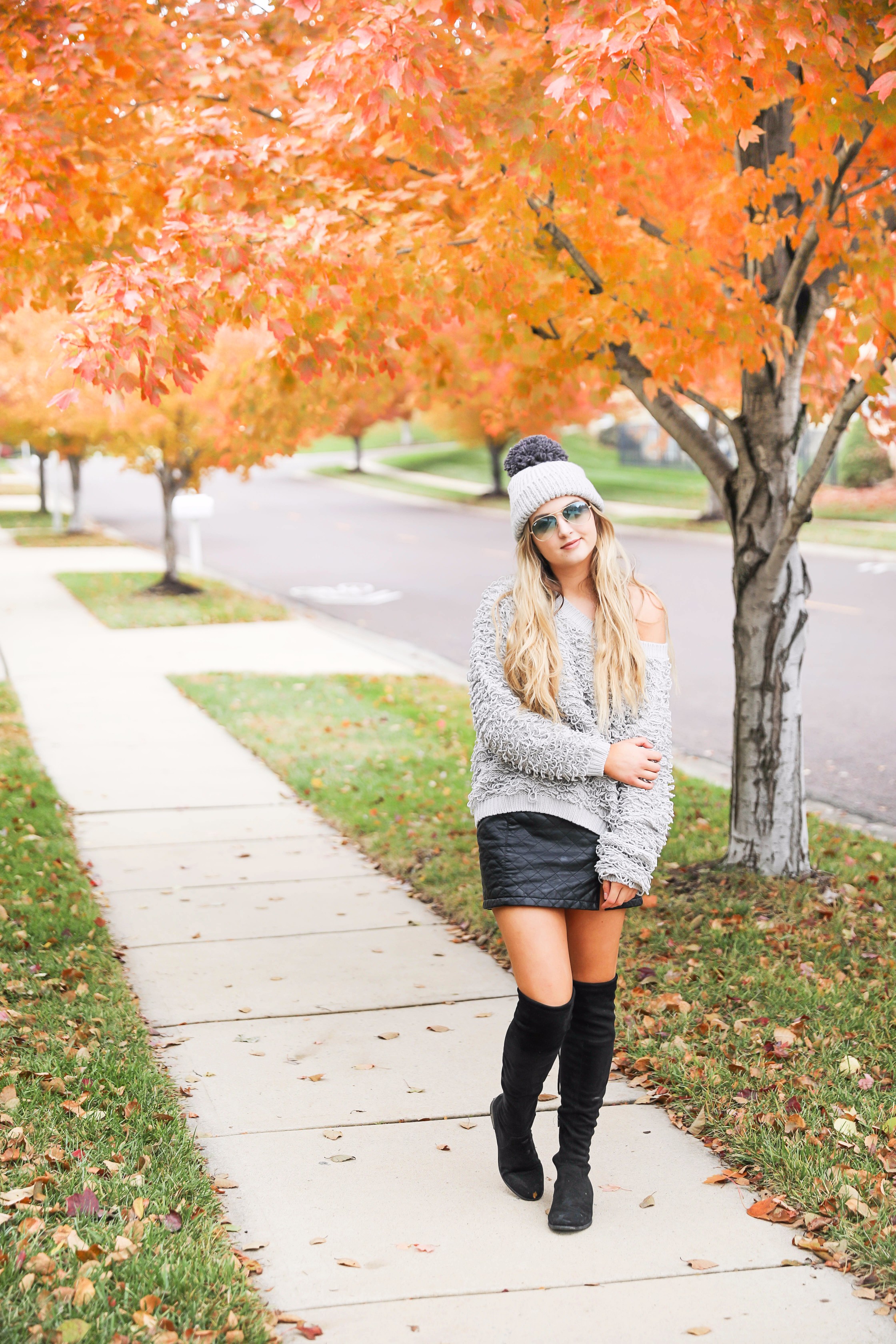 Grey loop sweater with black faux leather skirt and over the knee black boots! Paired with a pom beanie for colder days. Such a cute fall and winter outfit! Find the details on fashion blog daily dose of charm by lauren lindmark