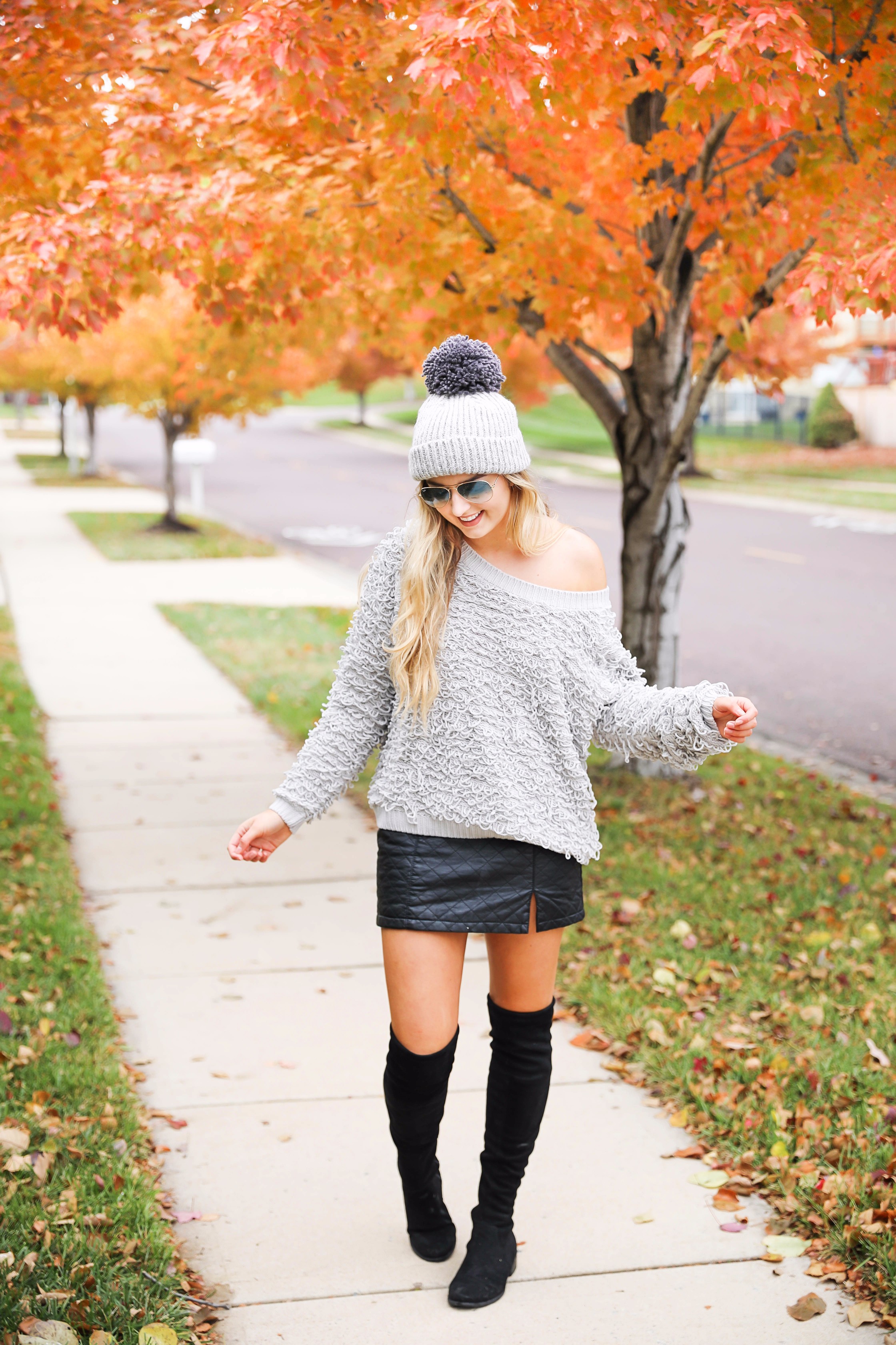 Grey loop sweater with black faux leather skirt and over the knee black boots! Paired with a pom beanie for colder days. Such a cute fall and winter outfit! Find the details on fashion blog daily dose of charm by lauren lindmark