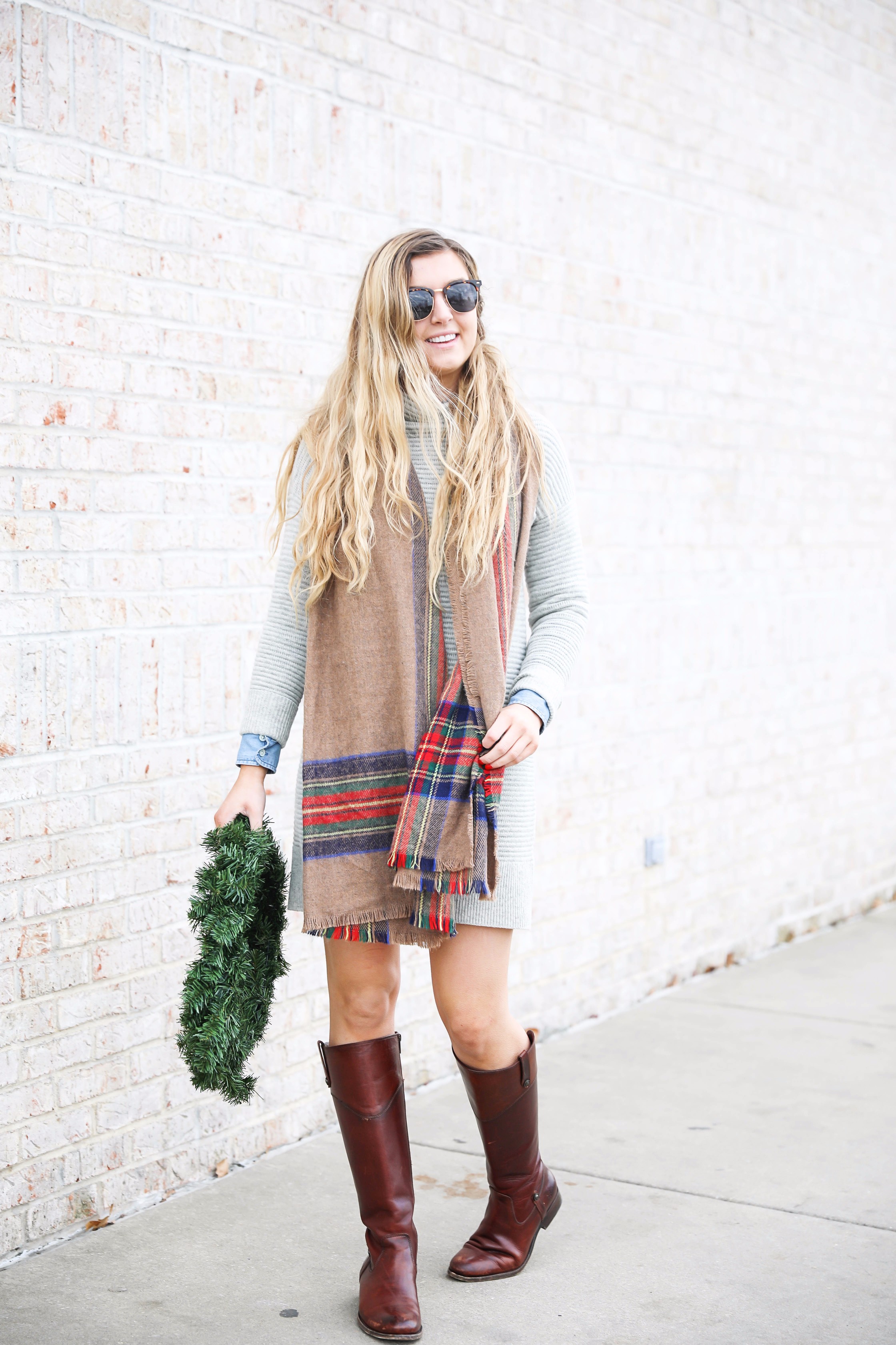 Grey sweater dress layered wtih a chambray top and plaid scarf! Paired with my favorite riding boots by frye boots! Photos taken with a christmas wreath. Christmas wreath photos by lauren lindmark on the blog daily dose of charm