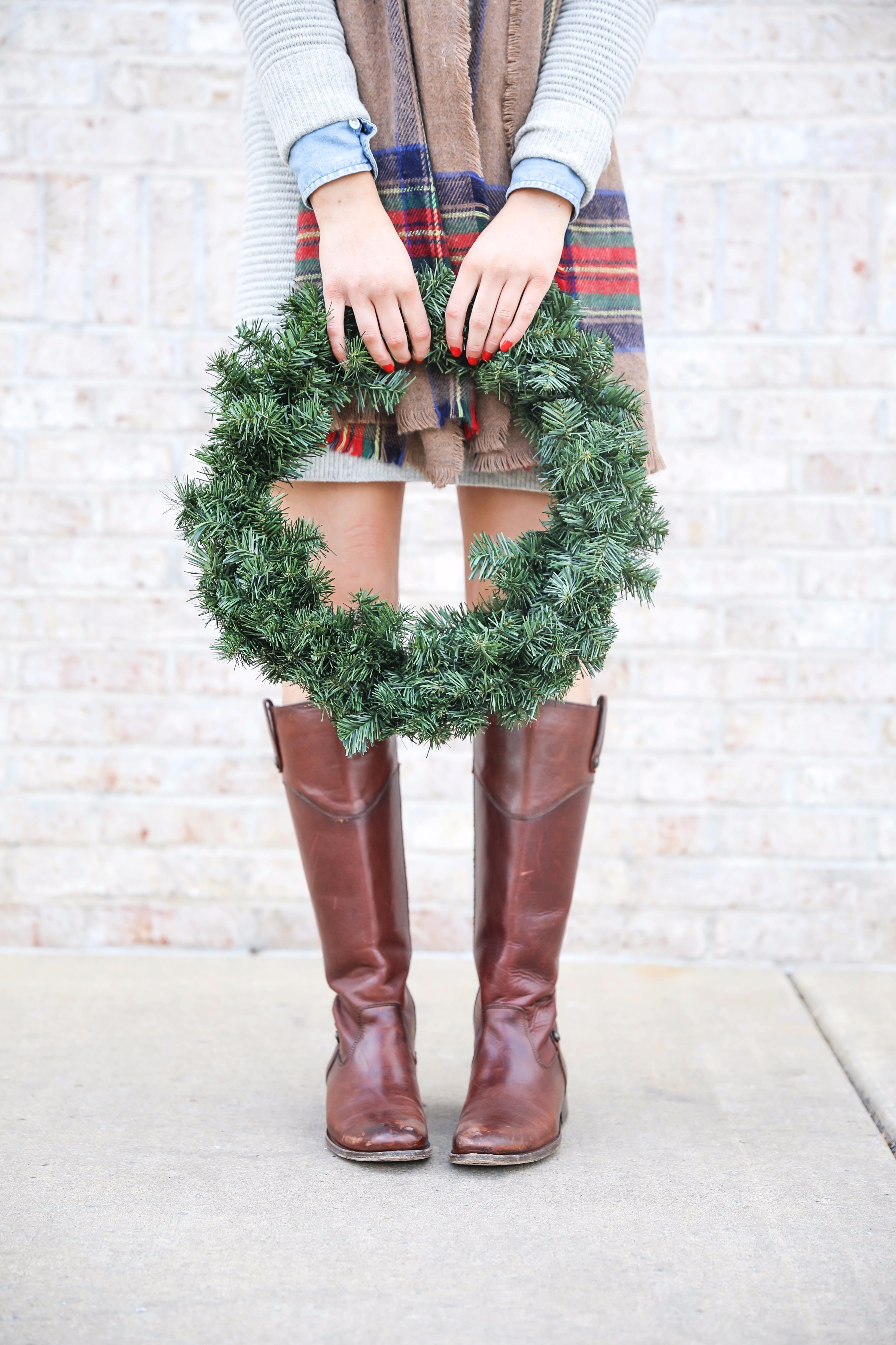 Grey sweater dress layered wtih a chambray top and plaid scarf! Paired with my favorite riding boots by frye boots! Photos taken with a christmas wreath. Christmas wreath photos by lauren lindmark on the blog daily dose of charm