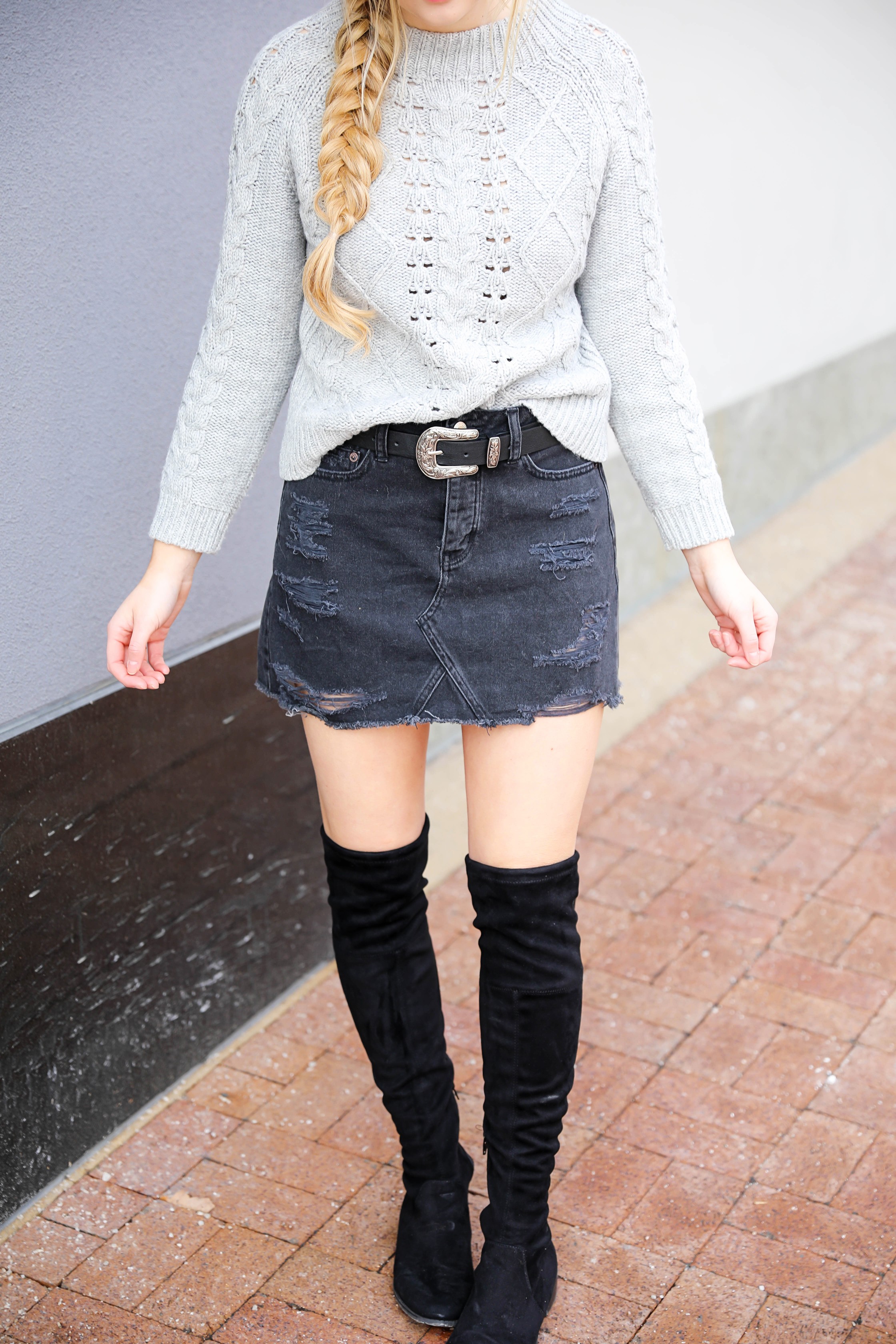 Edgy meets cozy Adorable ripped black denim skirt with over the knee black boots Paired with a cozy grey J.Crew cable knit sweater Details on fashion blog daily dose of charm by