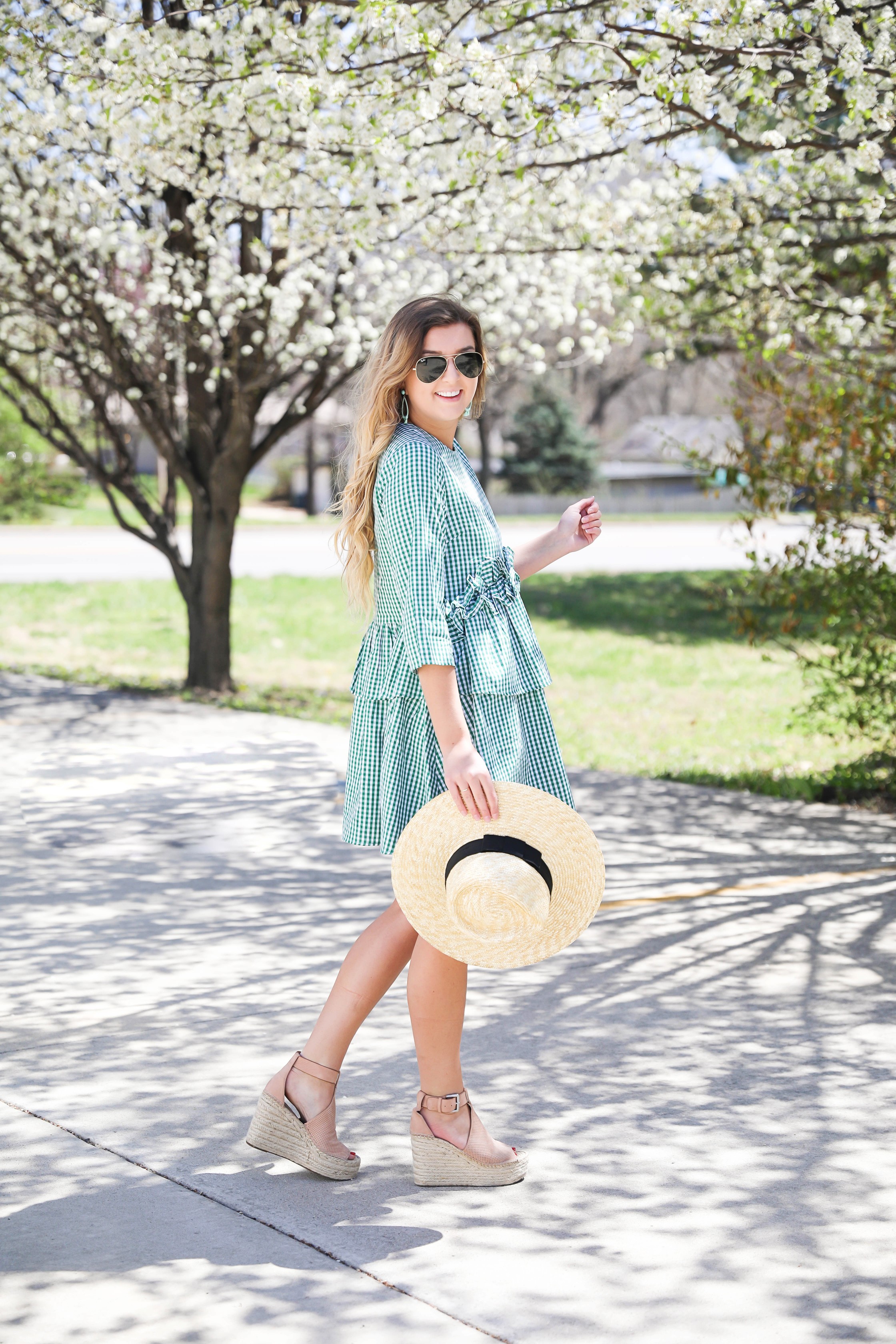 Green gingham dress perfect for spring days or days on the beach! I paired it with a straw hat and blue earrings! The most beautiful spring blooming trees were in the background making this spring fashion look perfection! Details on fashion blog daily dose of charm by lauren lindmark