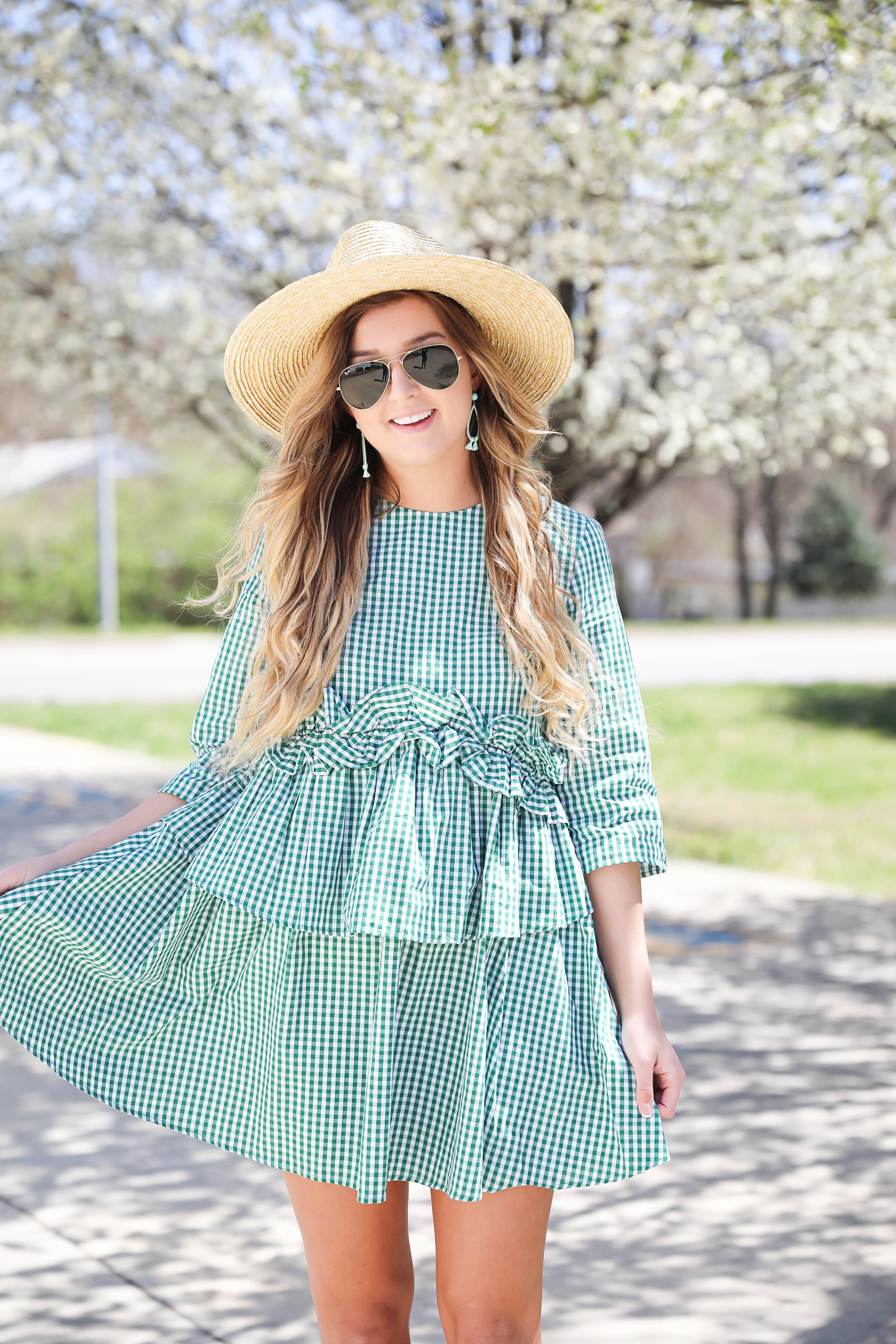 Green gingham dress perfect for spring days or days on the beach! I paired it with a straw hat and blue earrings! The most beautiful spring blooming trees were in the background making this spring fashion look perfection! Details on fashion blog daily dose of charm by lauren lindmark