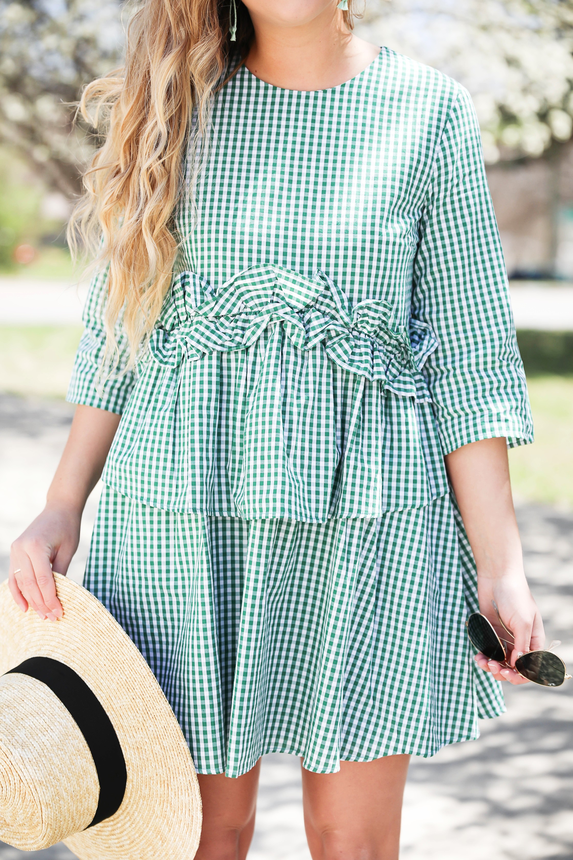 Green gingham dress perfect for spring days or days on the beach! I paired it with a straw hat and blue earrings! The most beautiful spring blooming trees were in the background making this spring fashion look perfection! Details on fashion blog daily dose of charm by lauren lindmark