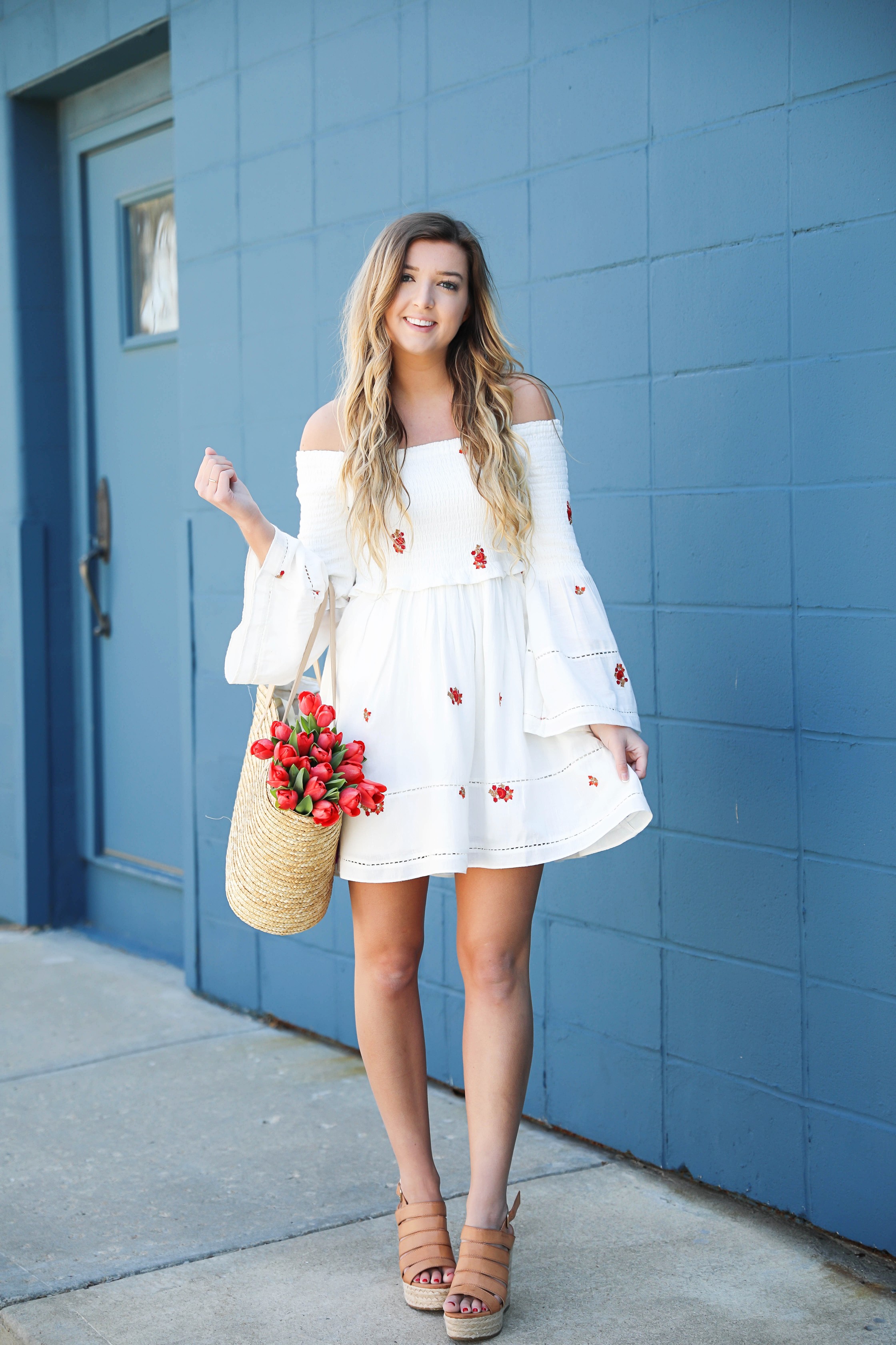 White off the shoulder dress with red embroidery by Free People! Love this look with red tulips in a straw bag and cute wedges! Perfect spring look on fashion blog daily dose of charm by lauren lindmark