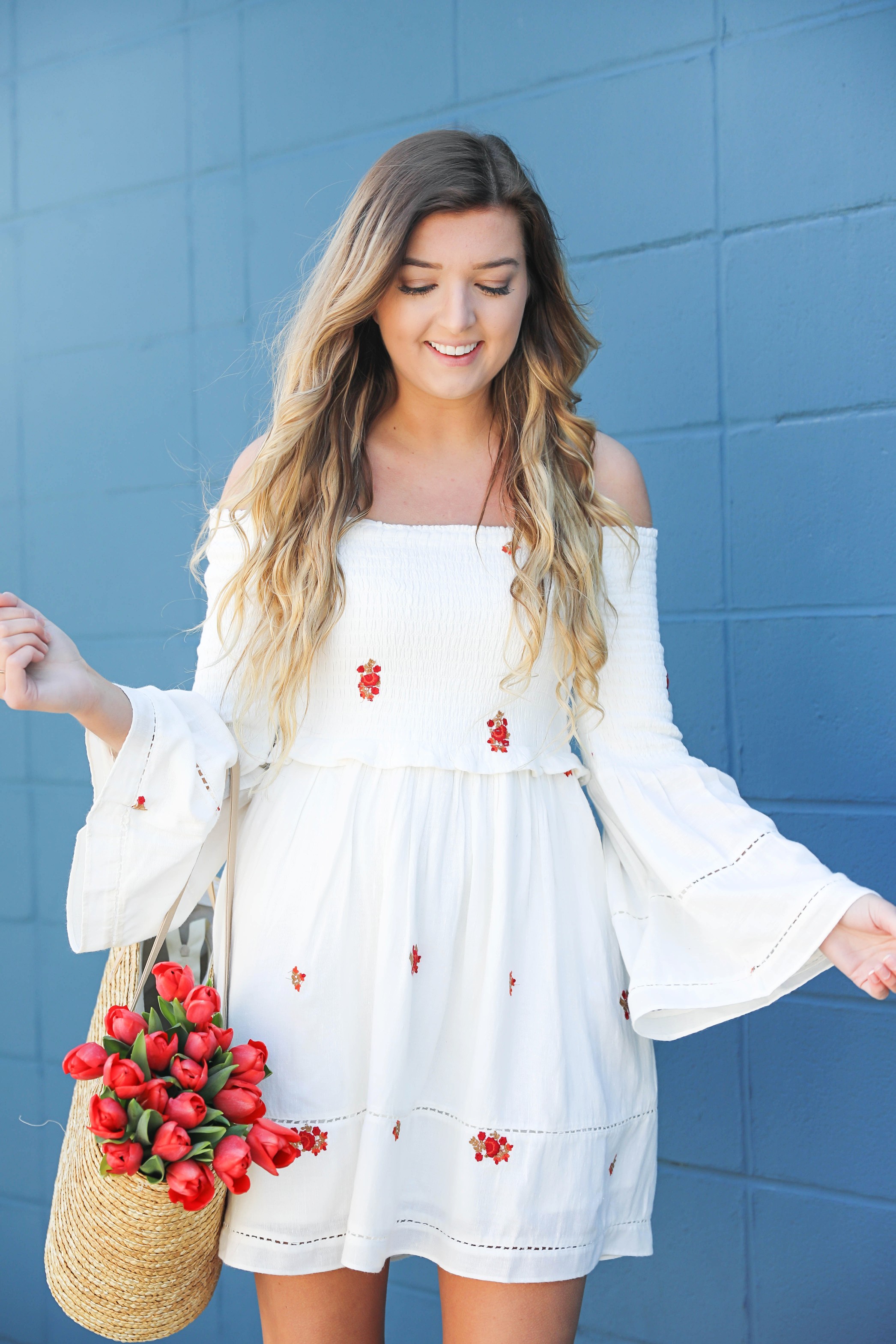 White off the shoulder dress with red embroidery by Free People! Love this look with red tulips in a straw bag and cute wedges! Perfect spring look on fashion blog daily dose of charm by lauren lindmark