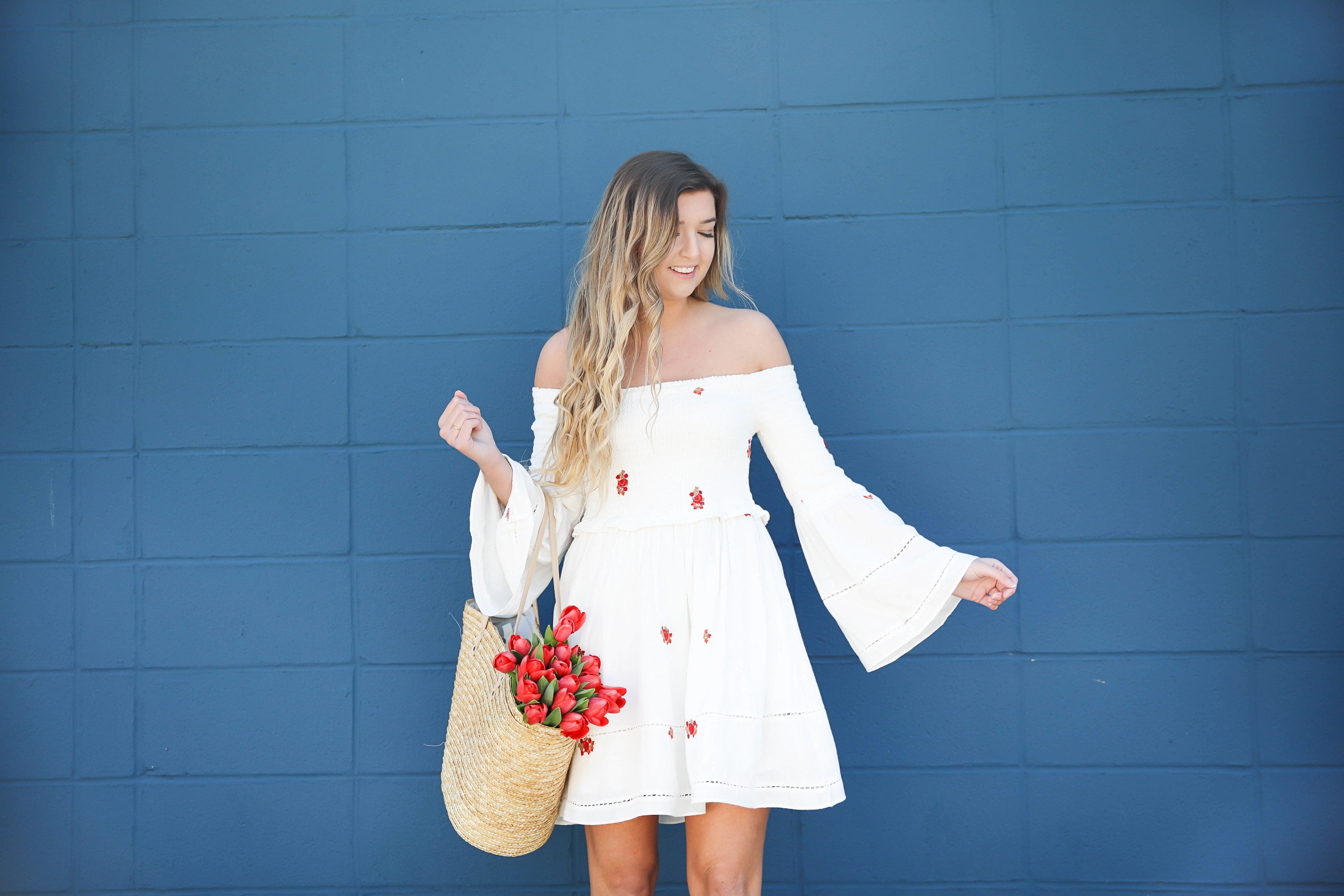 White off the shoulder dress with red embroidery by Free People! Love this look with red tulips in a straw bag and cute wedges! Perfect spring look on fashion blog daily dose of charm by lauren lindmark