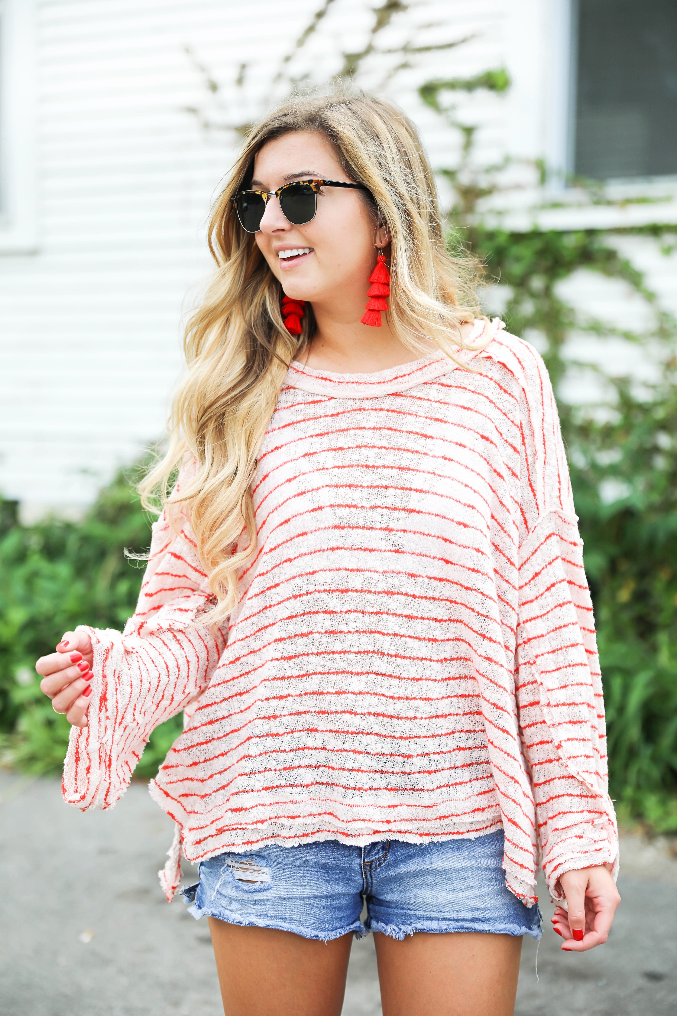 Striped red free people sweater with denim shorts and red tassel earrings! Perfect sweater for summer and days at the beach! Light weight summer sweater! Fourth of july outfit idea on fashion blog daily dose of charm by lauren lindmark