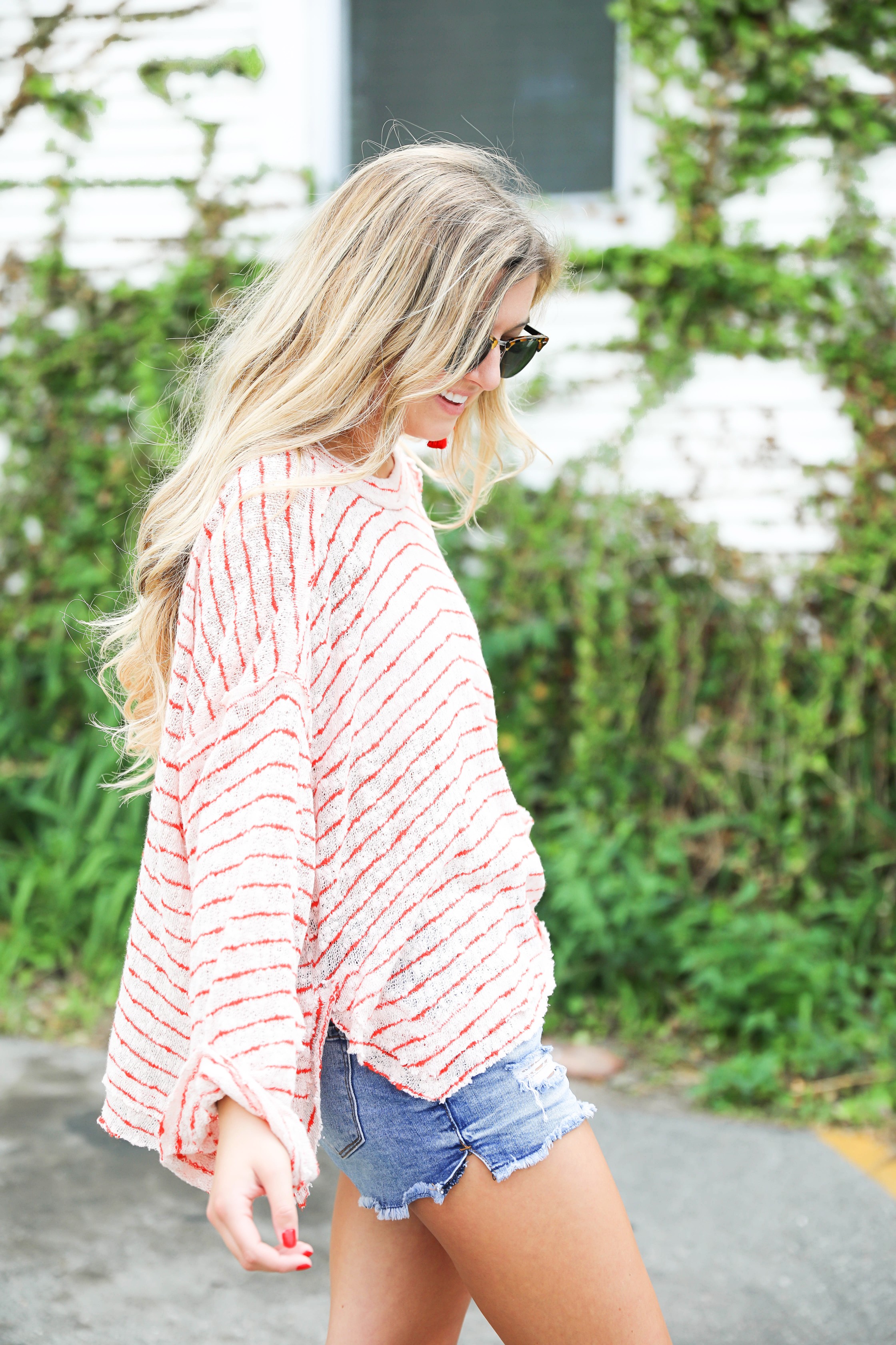 Striped red free people sweater with denim shorts and red tassel earrings! Perfect sweater for summer and days at the beach! Light weight summer sweater! Fourth of july outfit idea on fashion blog daily dose of charm by lauren lindmark