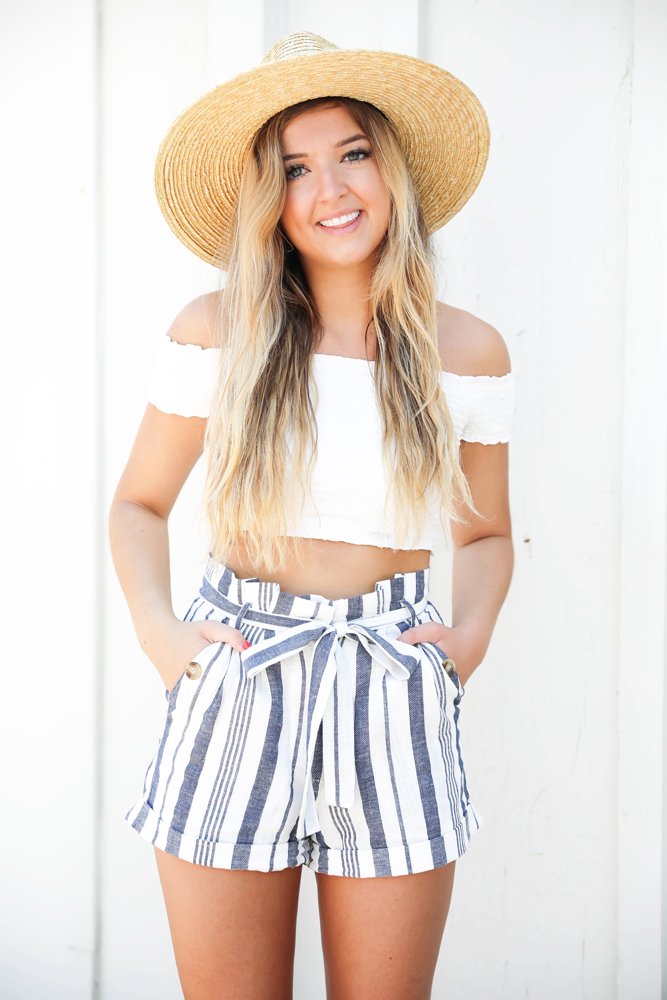 White off the shoulder crop top from Showpo paired with my favorite striped blue tied shorts from Nordstrom! I paired this look with a wide brim straw hat and my favorite Marc Fisher Espadrille wedges! This cute summer outfit is going to be on repeat! Details on fashion blog daily dose of charm by lauren lindmark
