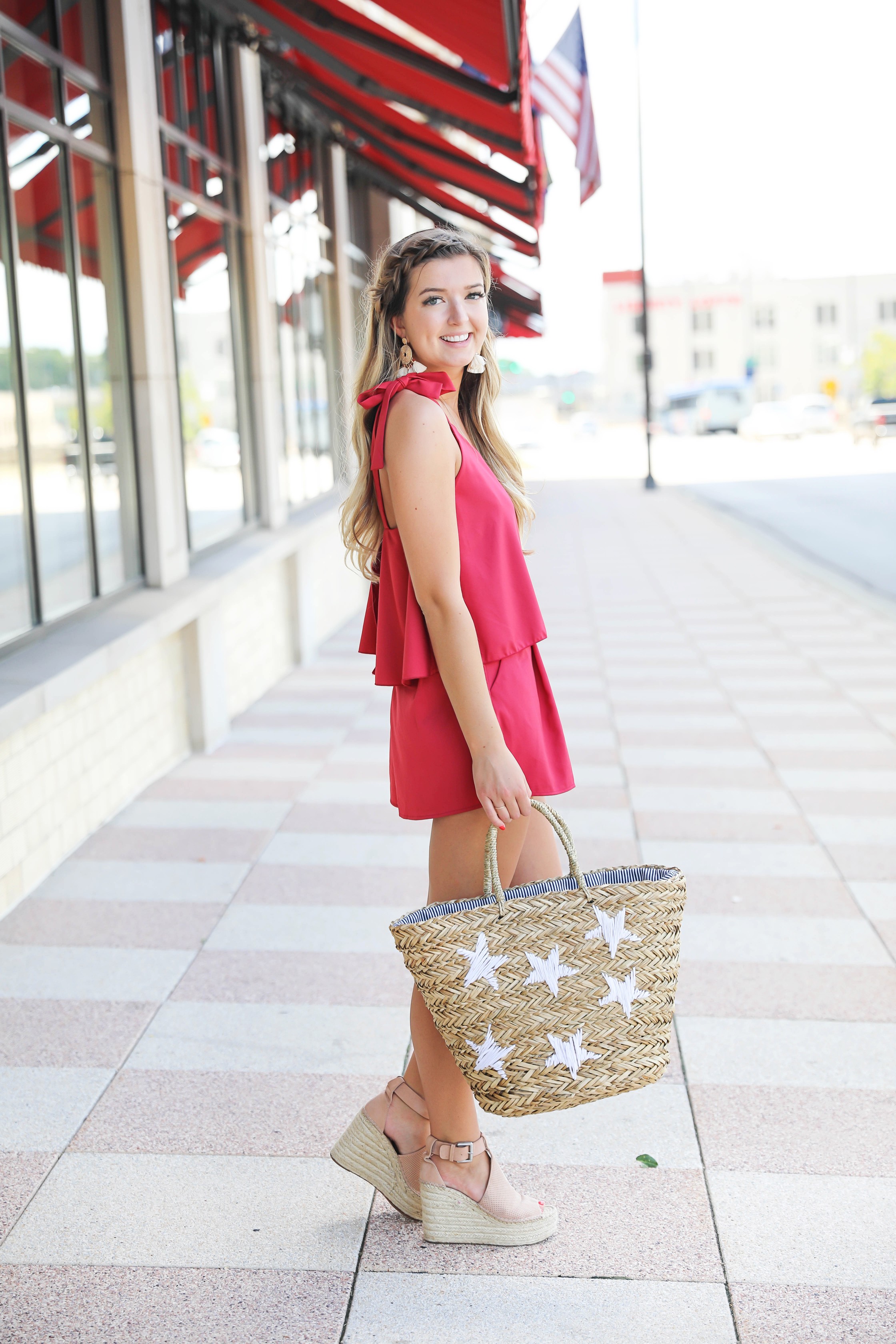 Red romper with cute tied shoulders! The cutest summer romper for Fourth of July! Paired with a star beach bag for fourth of July! Outfit details on fashion blog daily dose of charm by lauren lindmark