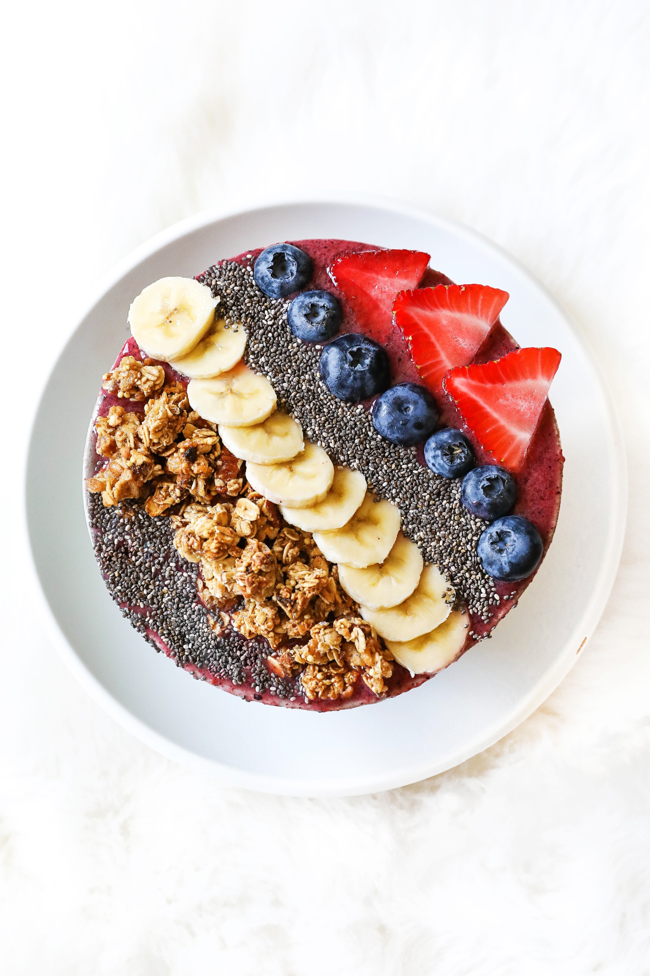 Smoothie bowl with acai, bananas, strawberries, blueberries, chia seeds, granola, and more! Healthy breakfast ideas! Easy low calorie recipe on the blogpost what I eat in a day! Details on lifestyle blog daily dose of charm by lauren lindmark