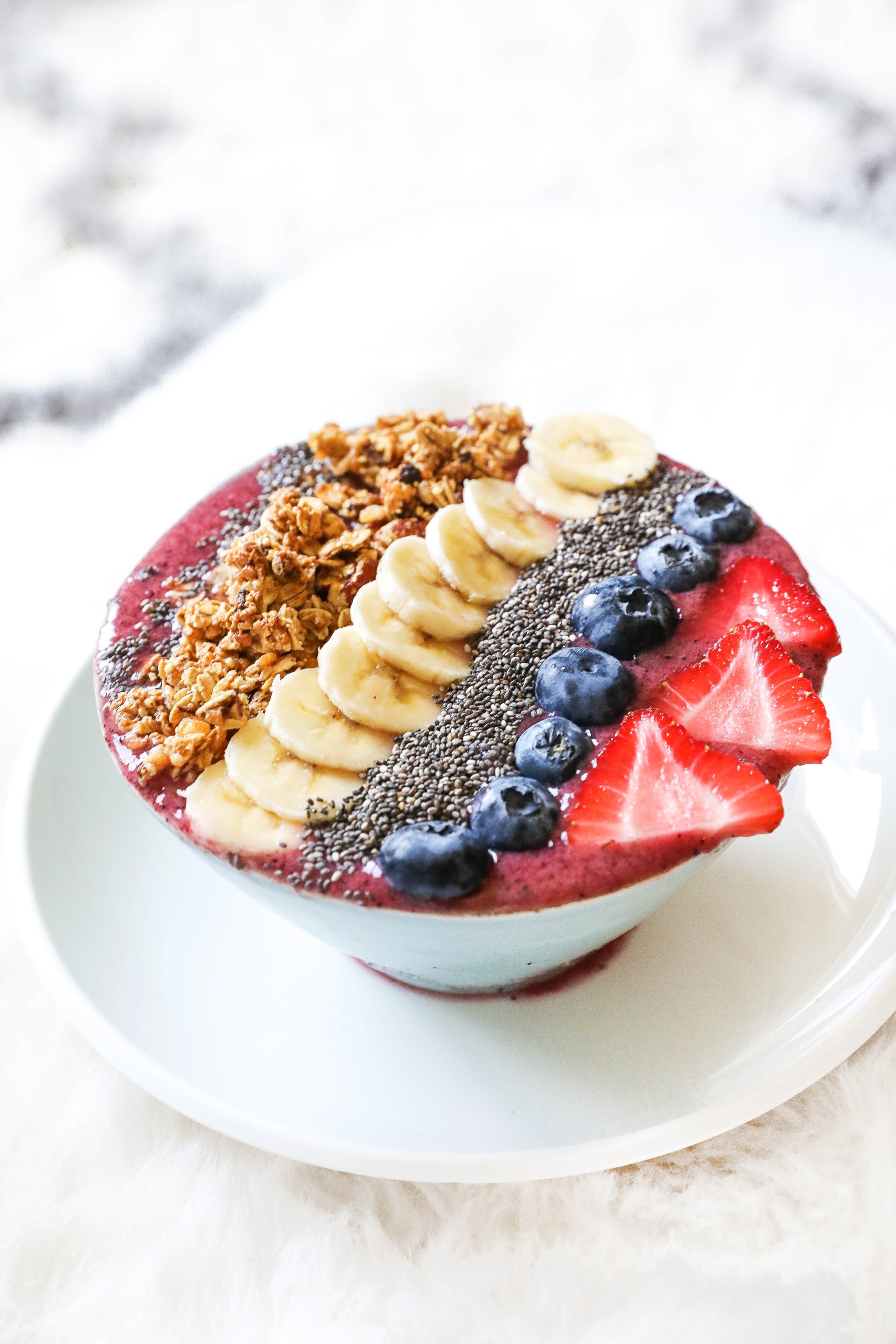 Smoothie bowl with acai, bananas, strawberries, blueberries, chia seeds, granola, and more! Healthy breakfast ideas! Easy low calorie recipe on the blogpost what I eat in a day! Details on lifestyle blog daily dose of charm by lauren lindmark