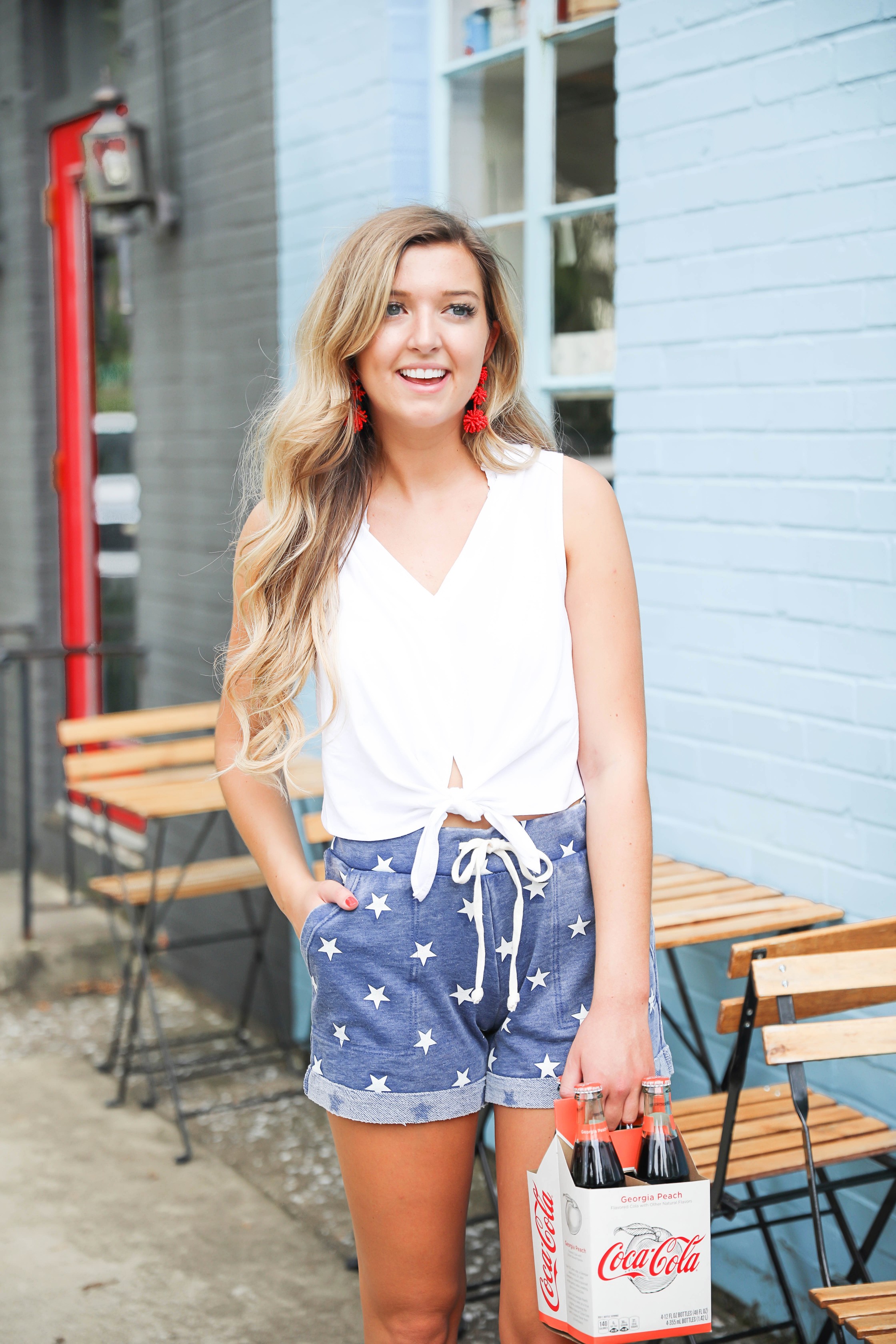 Fourth of july outfit inspo! I love these comfy blue star shorts! I paired it with this cute tied top! Such a fun coke bottle photoshoot! Red, white, and blue outfit details on fashion blogger daily dose of charm by lauren lindmark