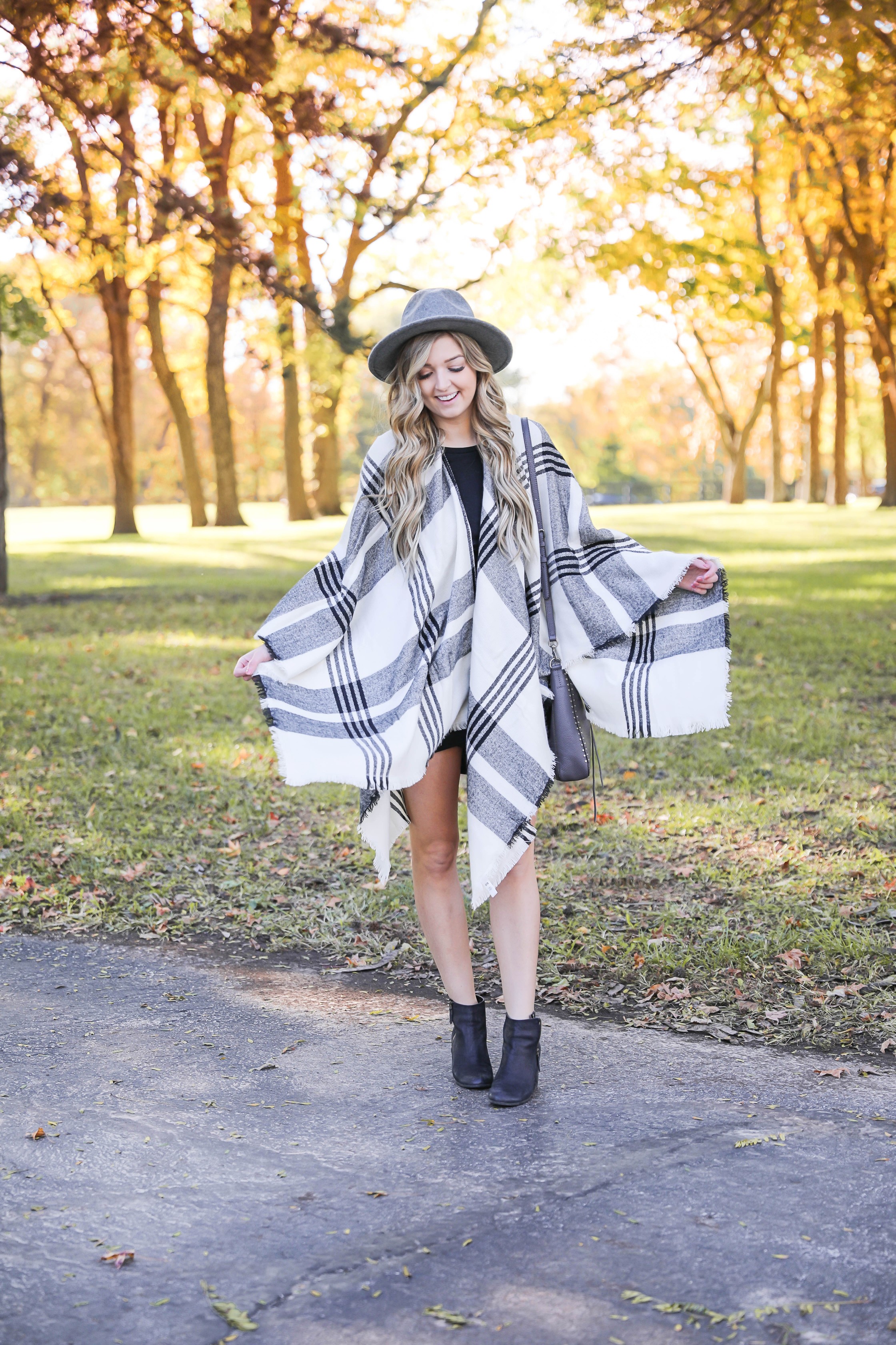 Plaid poncho wrapped around a tight black body con dress! I love these wraps for fall because they can double as scarves! This dress is by Leith from nordstrom and I am obsessed! Details on this fall fashion look and fall trees photoshoot can be found on fashion blog daily dose of charm by lauren lindmark